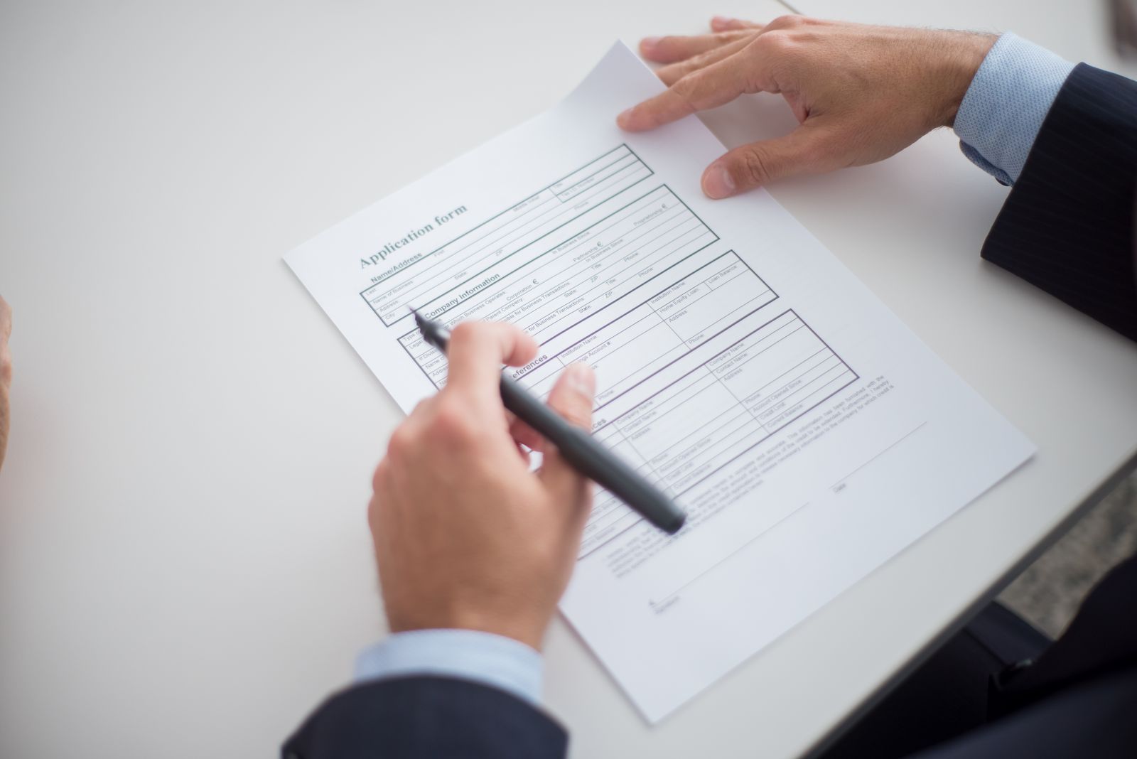 Hands with a pen going through a printed application form