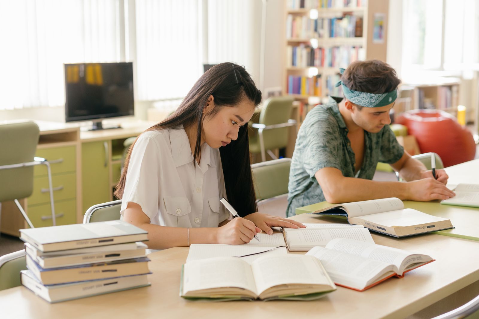 Students taking notes at a long table in a library