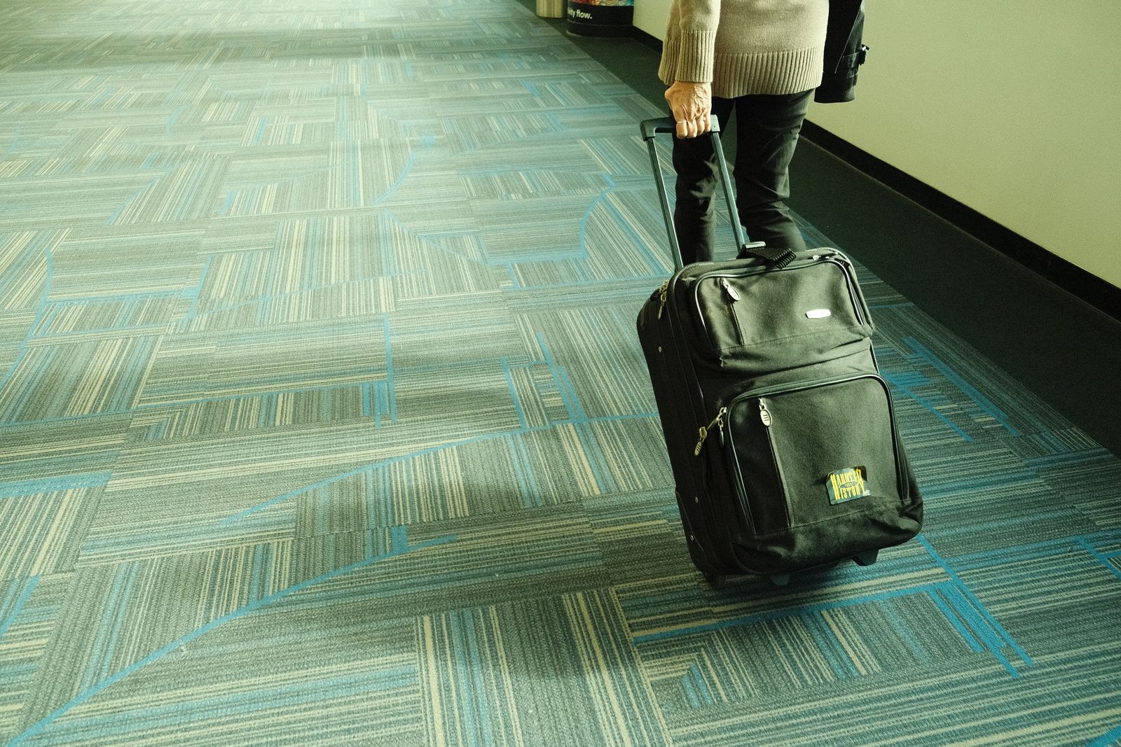 A traveller pulling a suitcase along an airport corridor