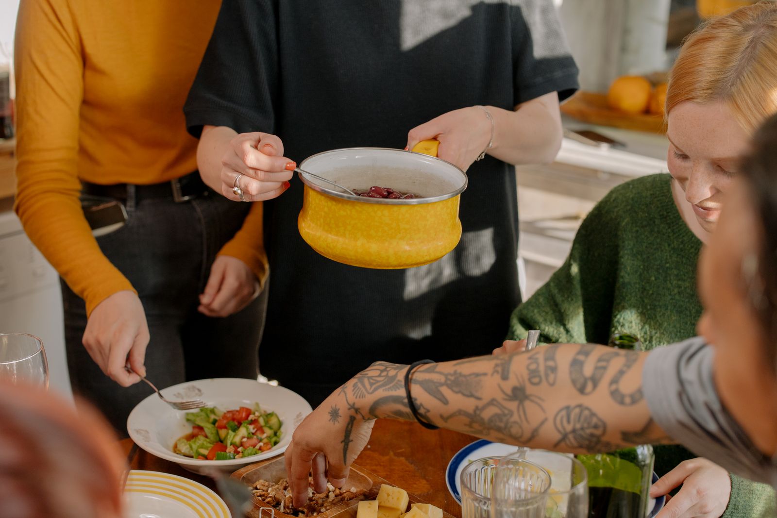 Friends sharing a vegetable dish at a kitchen table