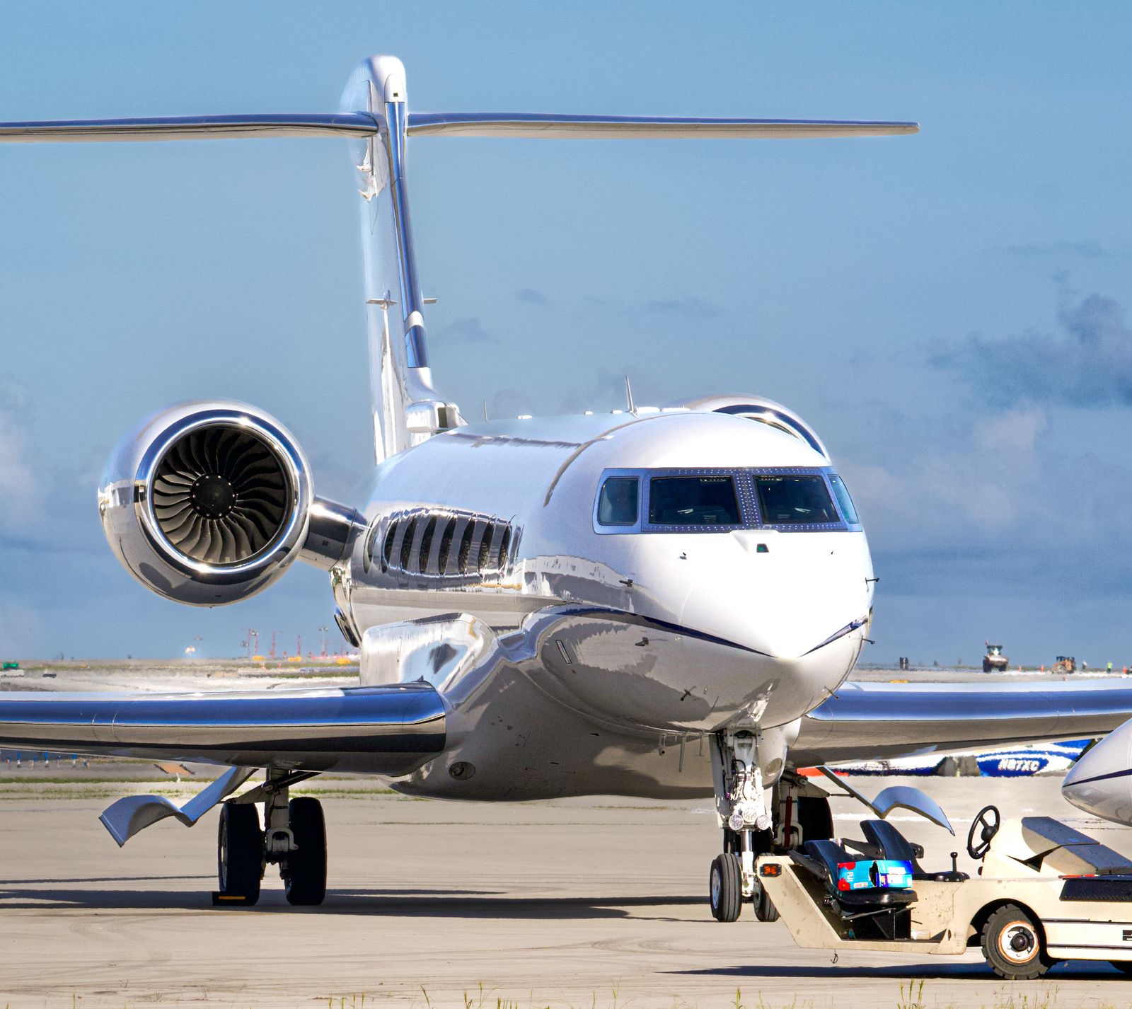 A white business jet parked on the apron under a blue sky