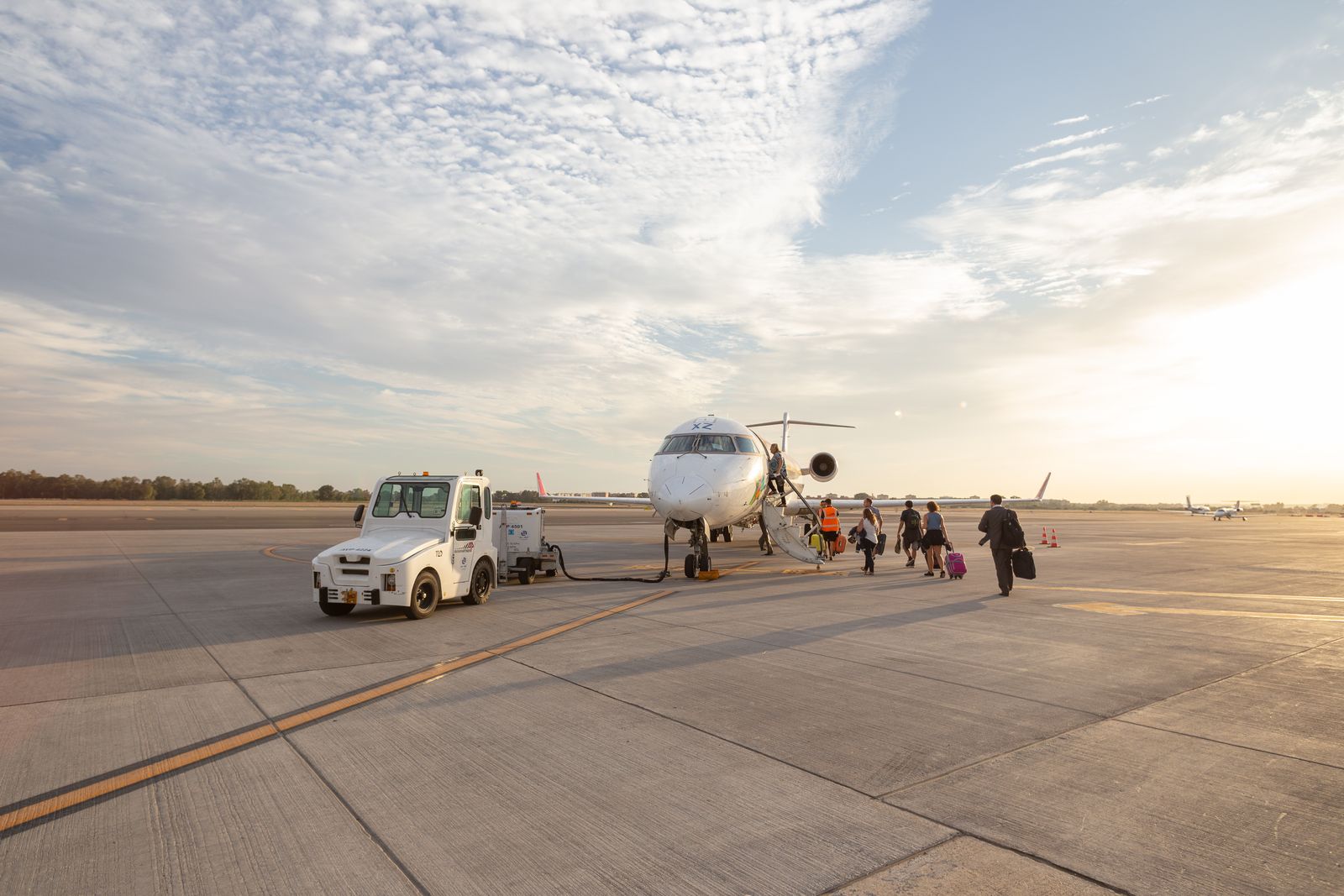 Passengers walking across the apron to a small jet at sunrise