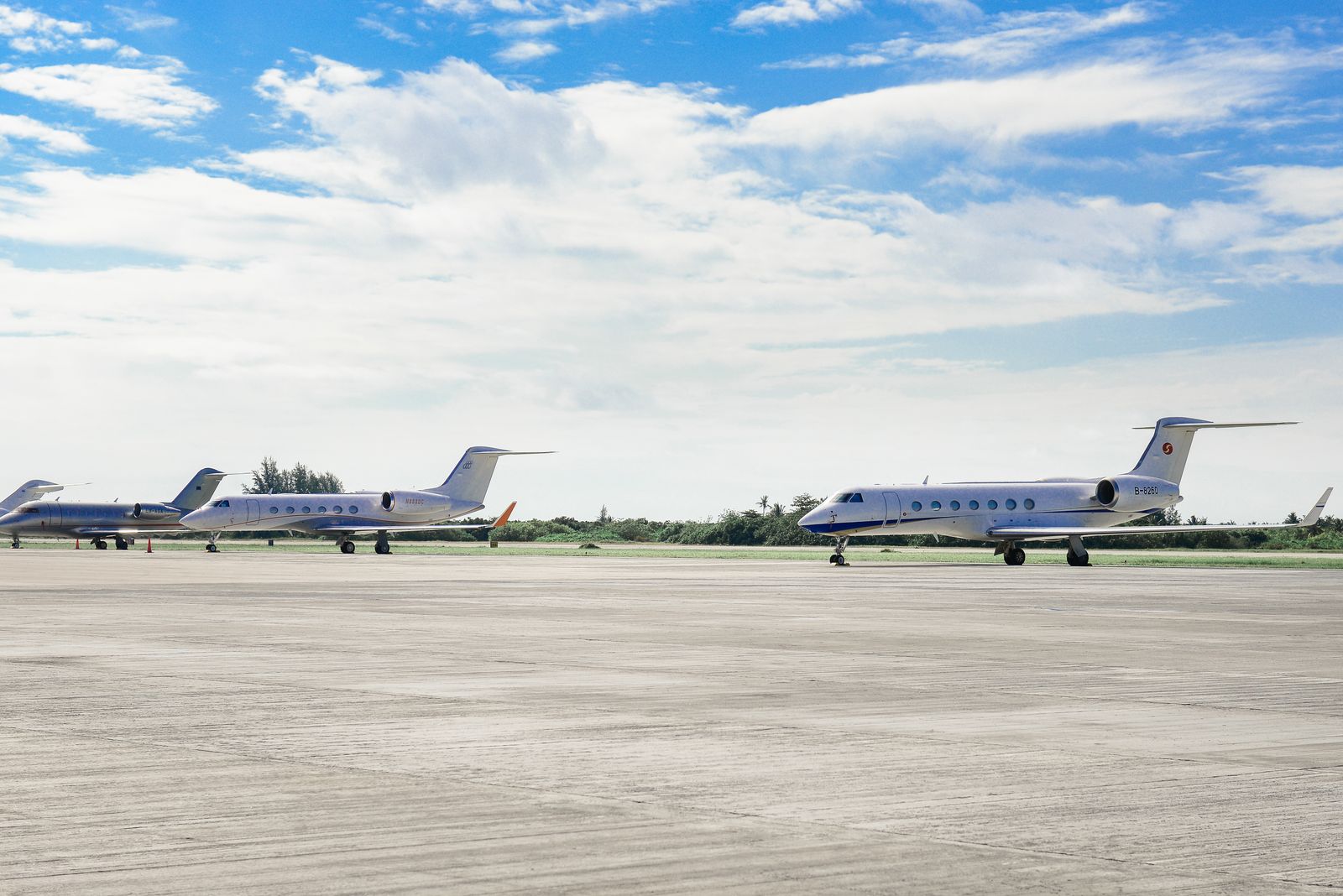 Business jets parked in a row on a quiet airfield