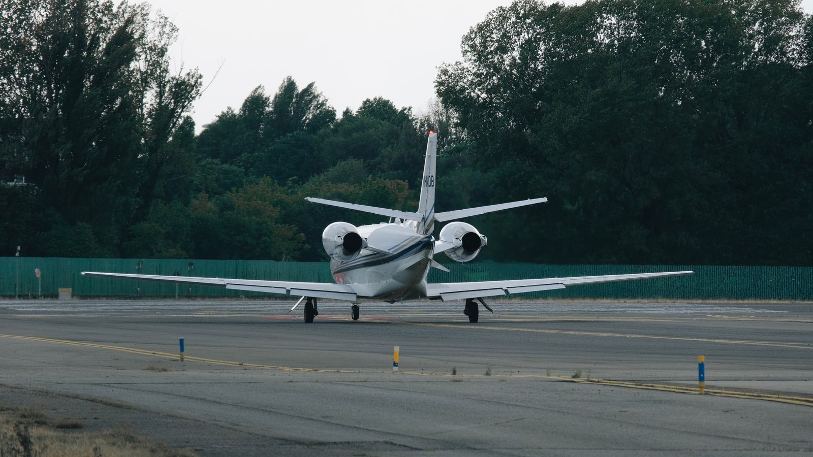 A business jet taxiing to the runway between rows of trees