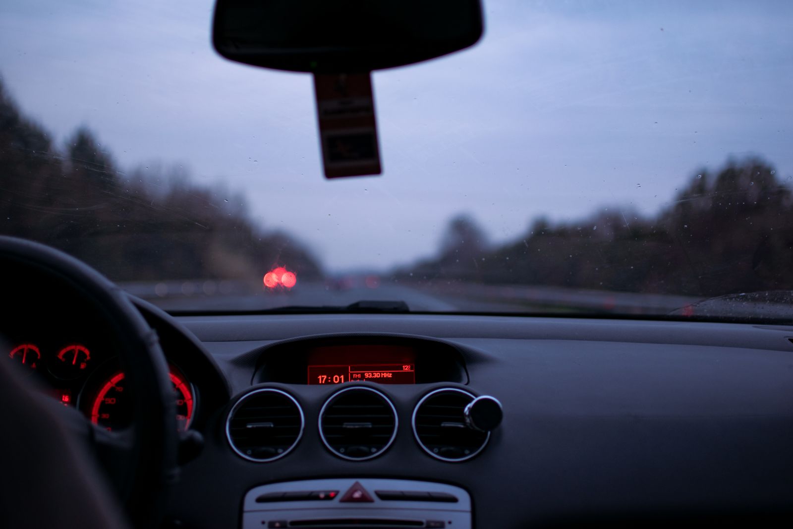 A car dashboard and windscreen on a motorway at dusk