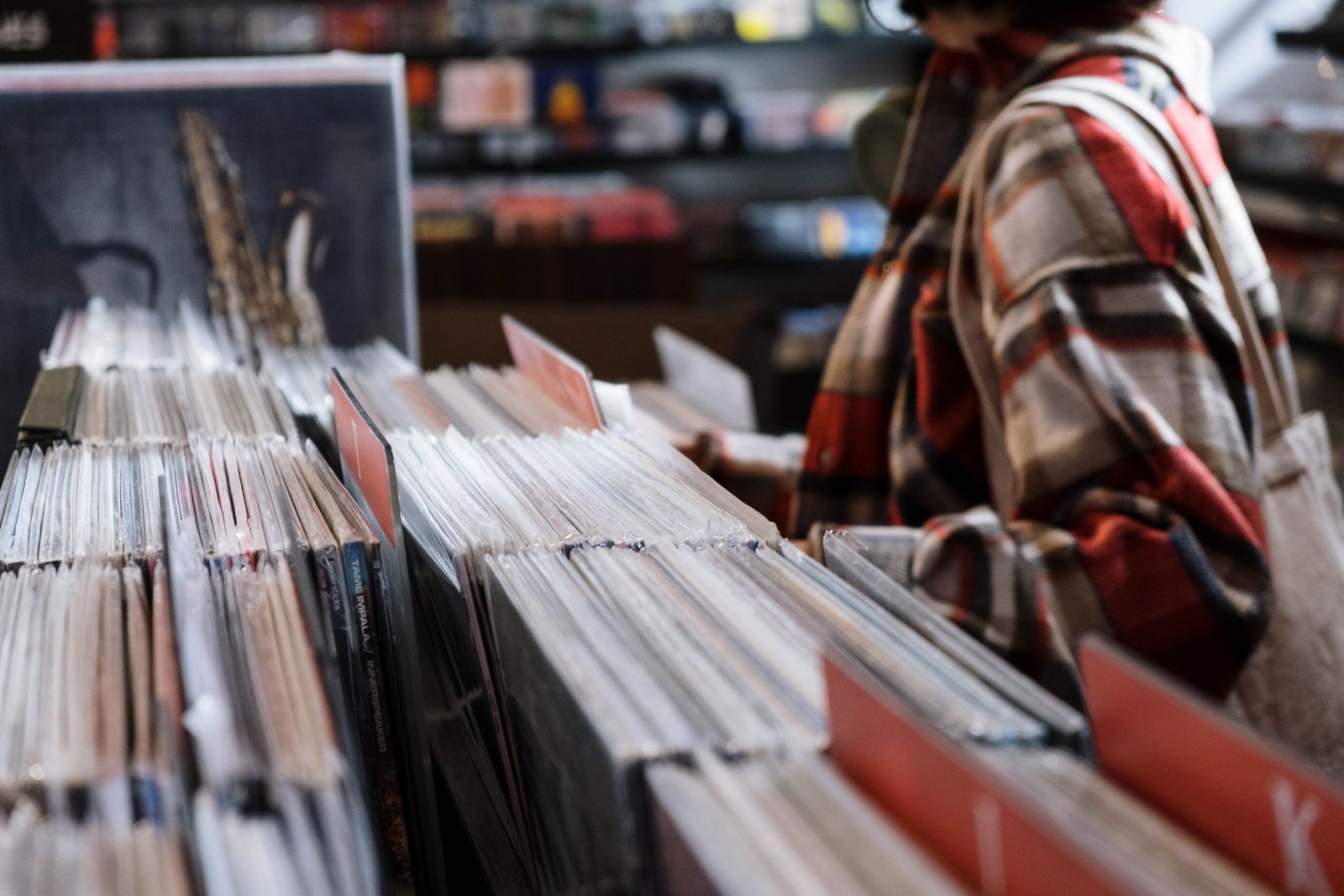 A hand flicking through second-hand records in a shop