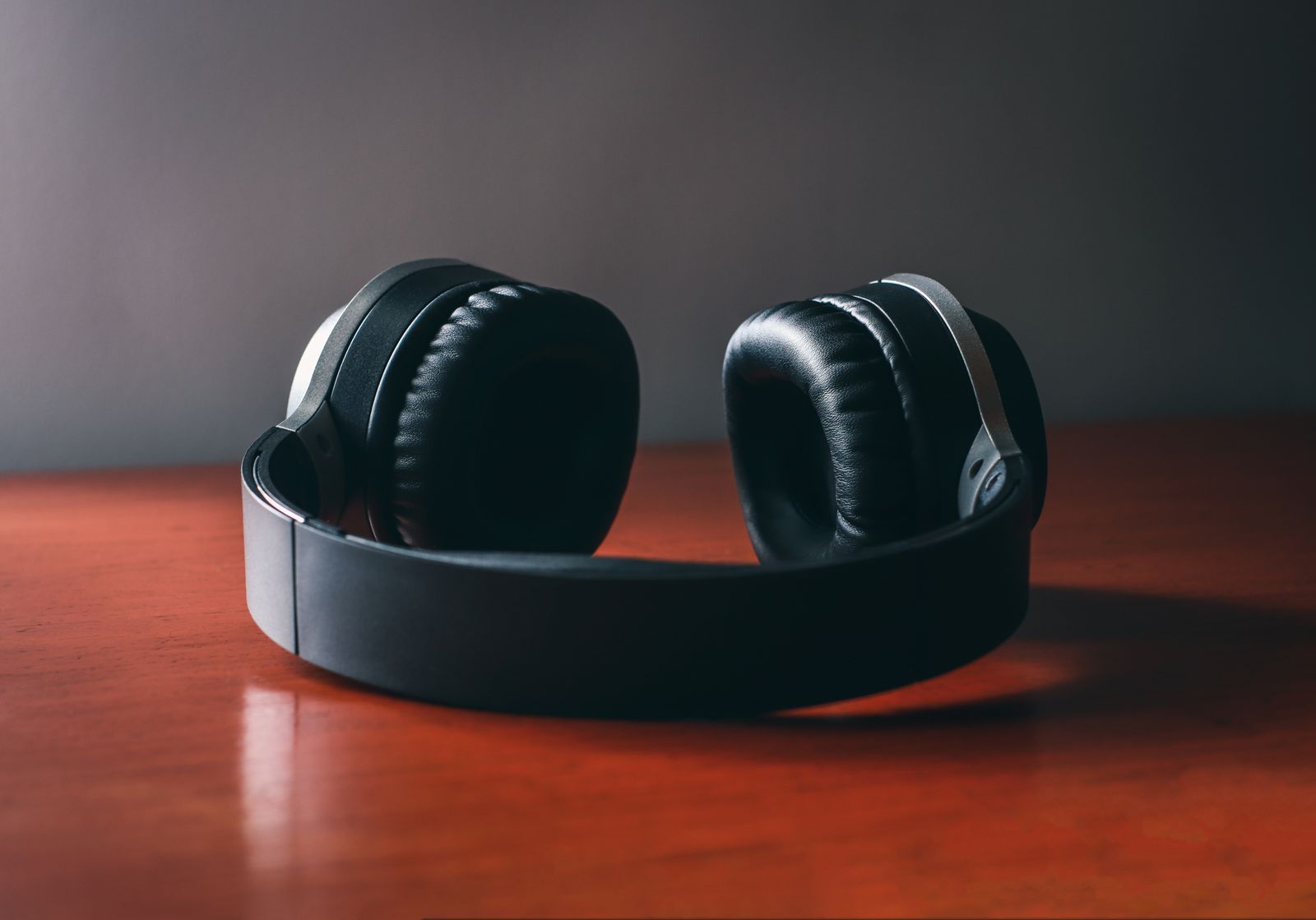 A pair of closed-back headphones lying on a wooden table