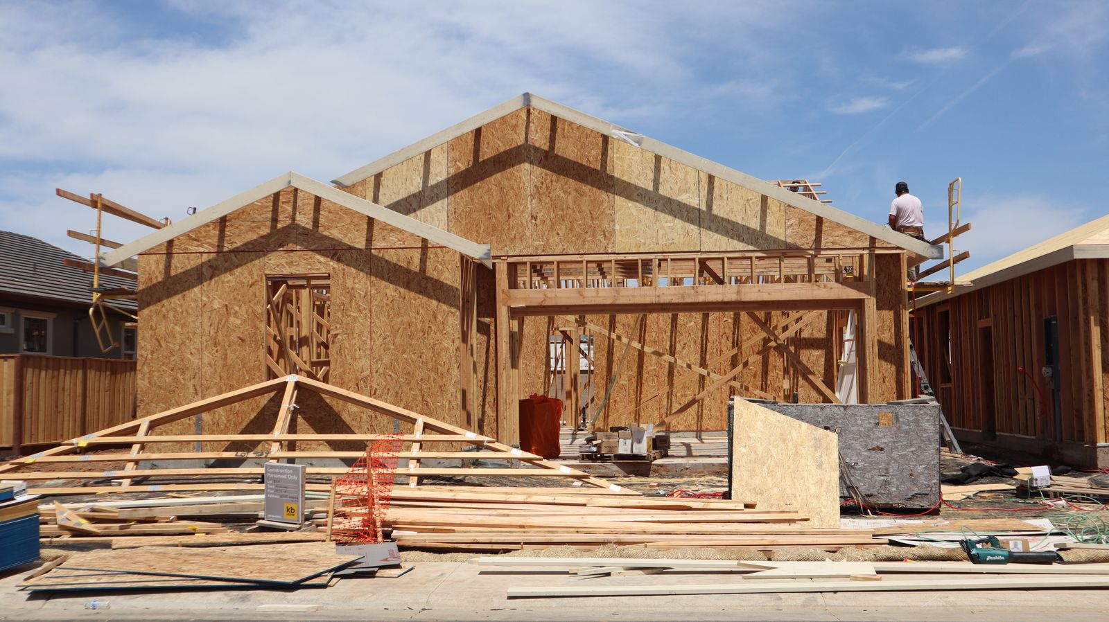Timber frame of a house going up, with a roof truss and stacked boards