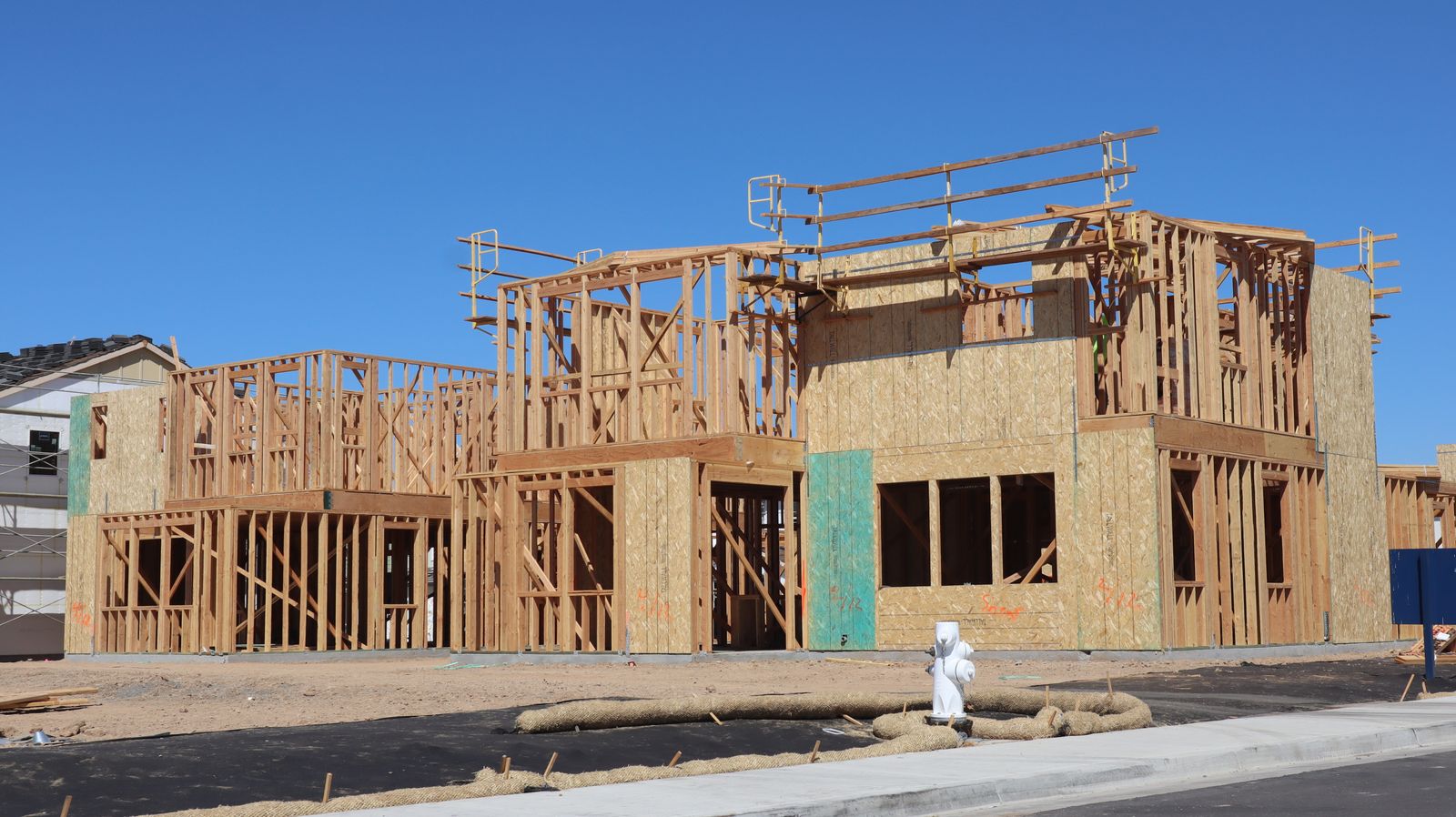 Timber-framed walls of new houses on a building site under a blue sky