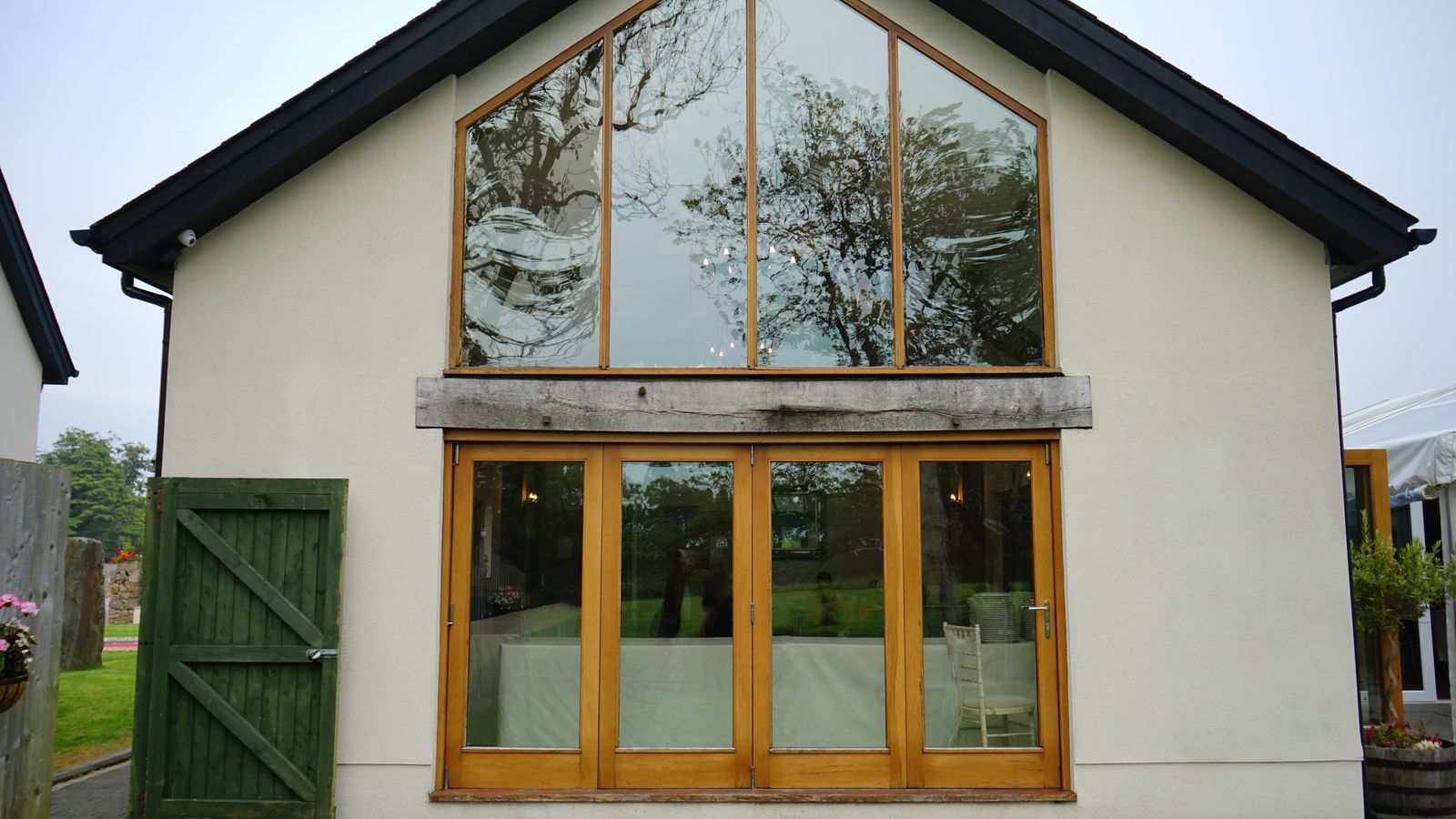 Rendered gable with tall timber-framed windows and a green timber door