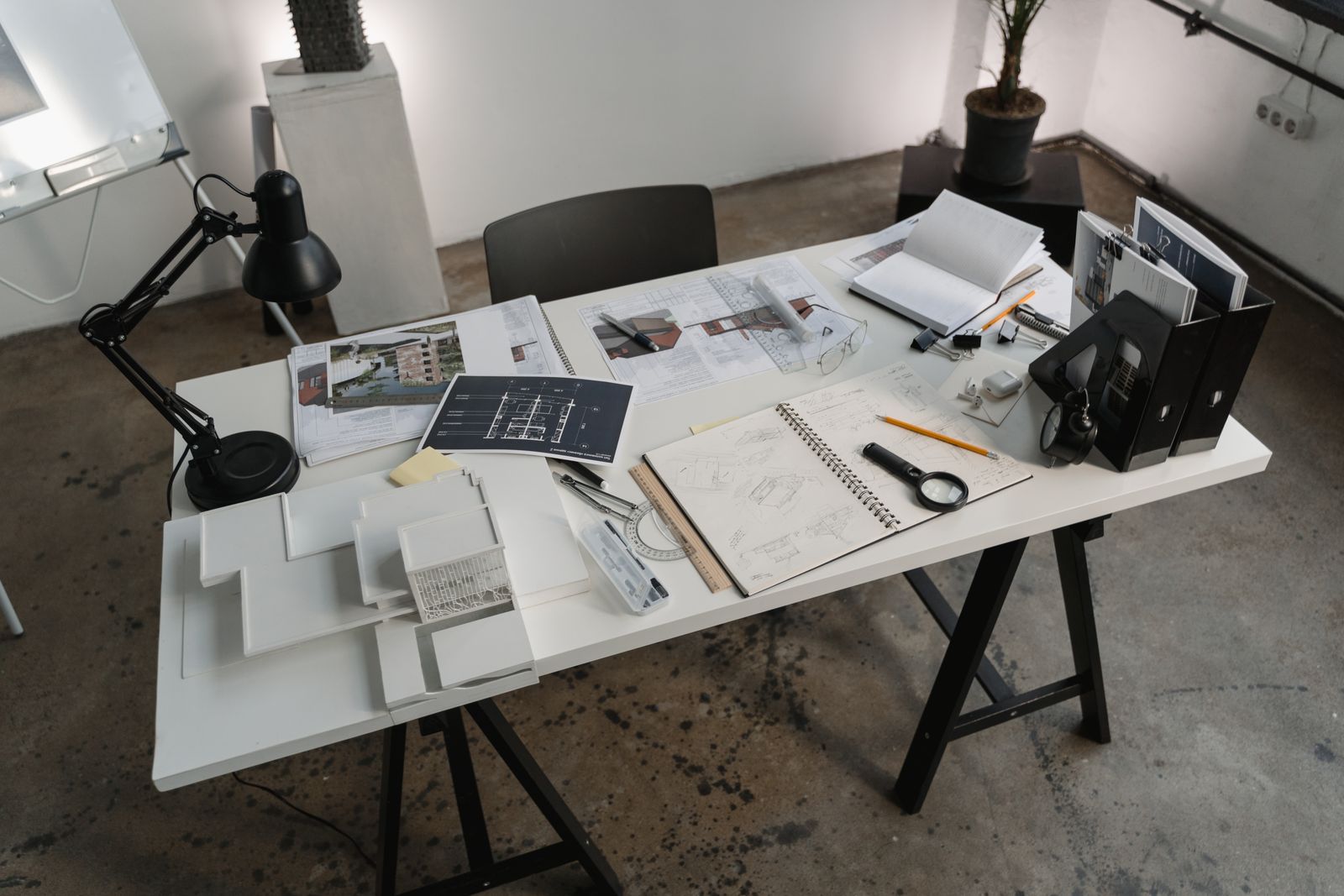 Architecture studio desk with card models, drawings and a lamp