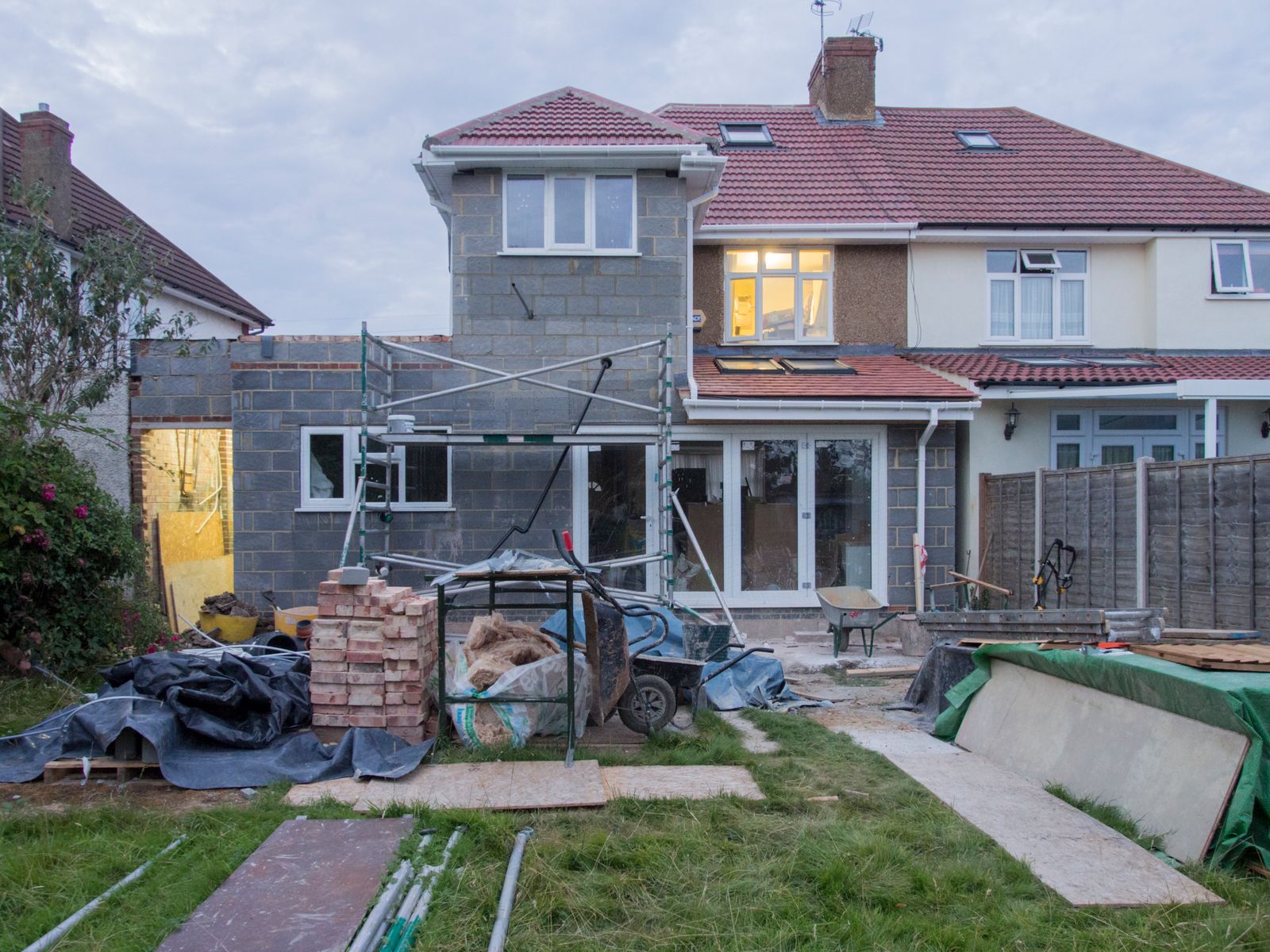 Rear extension of a semi-detached house with block walls up, scaffolding and materials in the garden