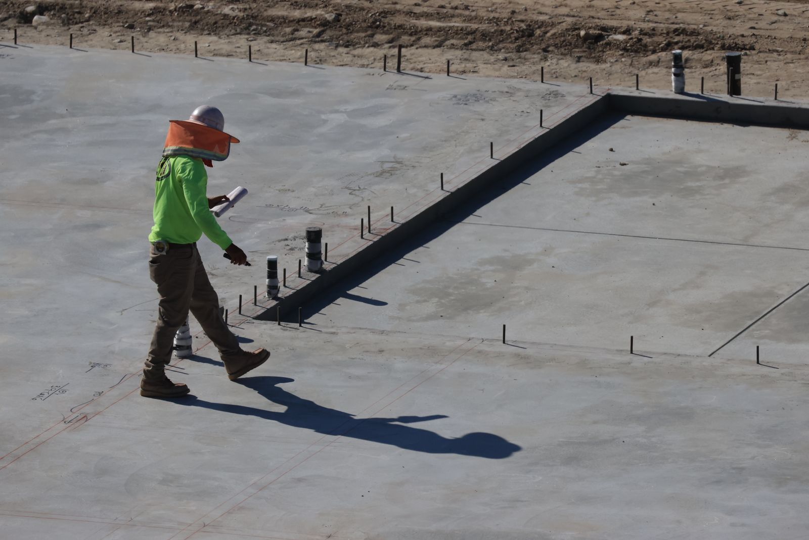 An engineer walking across a finished concrete slab, checking it before the frame goes up