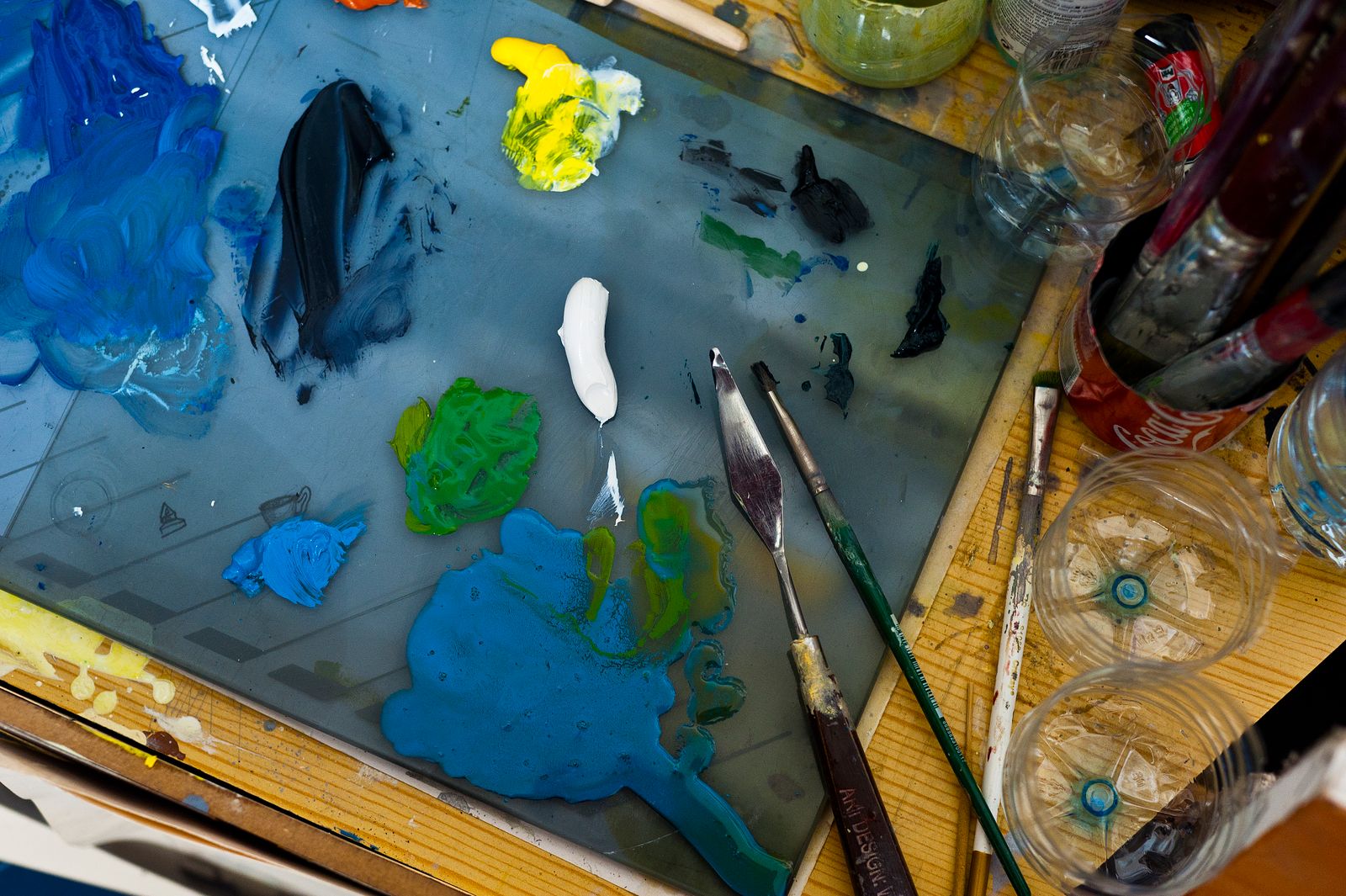 A palette of acrylic paints with brushes and a palette knife