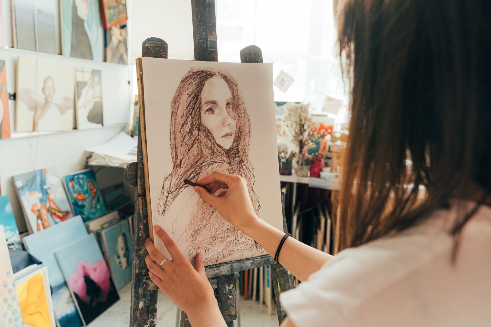 A student drawing a portrait in charcoal at an easel