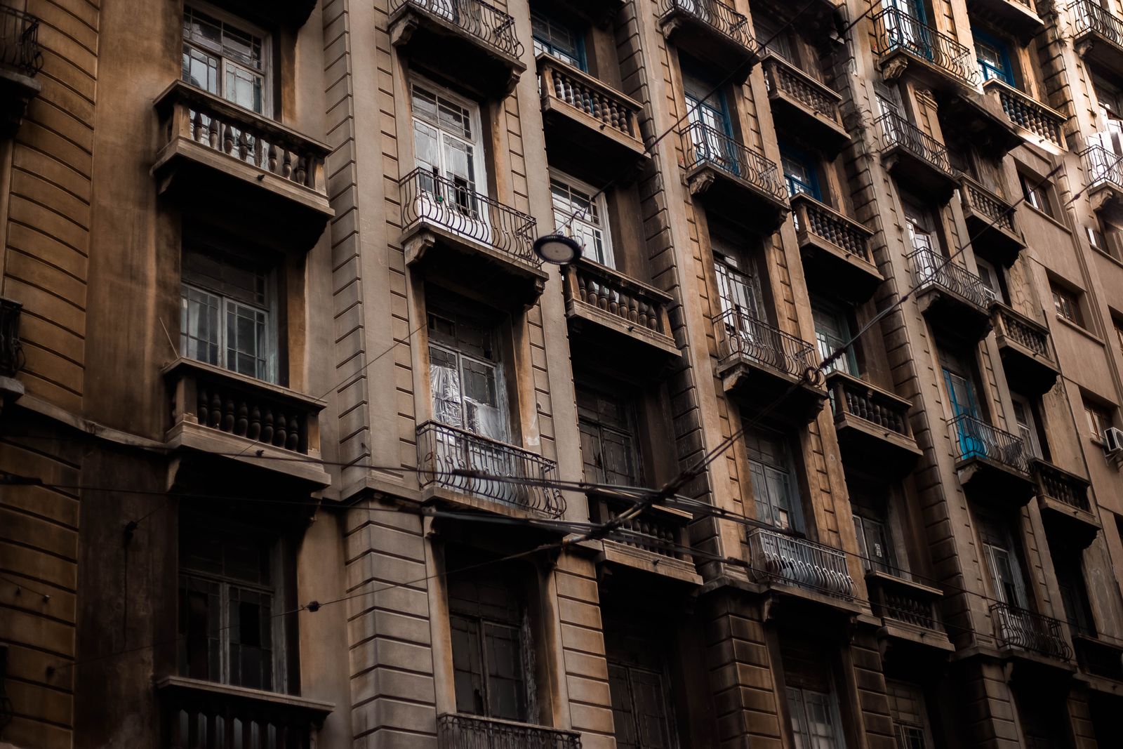 An old apartment block with rows of small balconies, seen from the street below