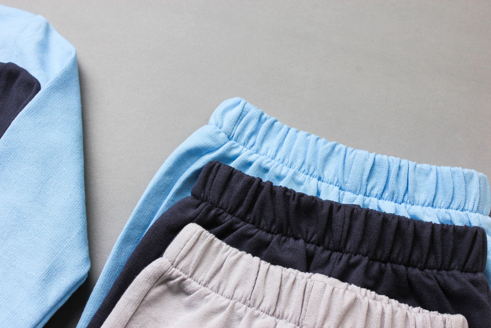 Folded baby trousers in pale blue, navy and soft pink cotton