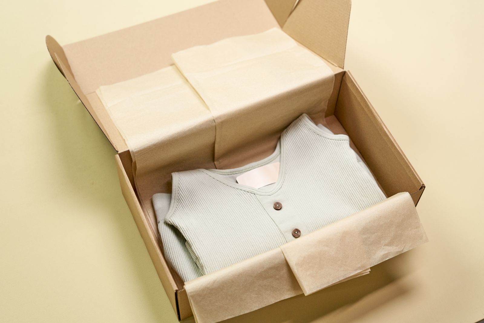 A small knitted cardigan folded in a gift box with tissue paper