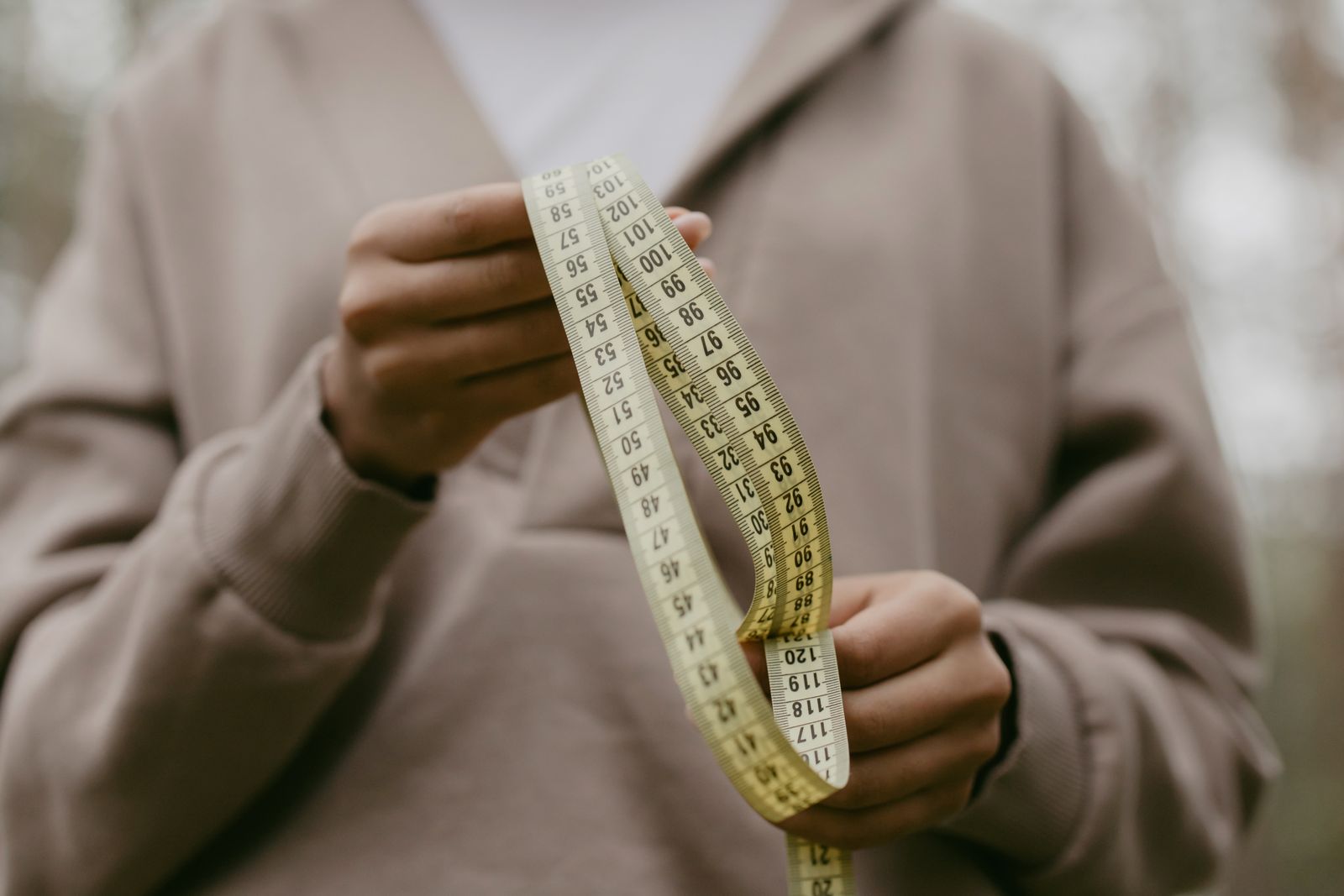 Hands holding a yellow tailor's measuring tape
