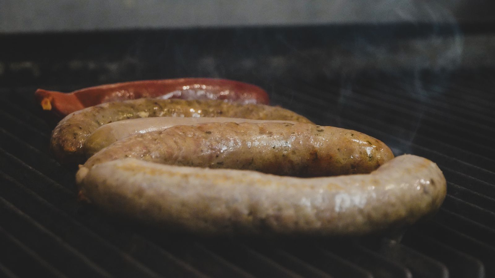 Coiled sausages browning on a smoker grate