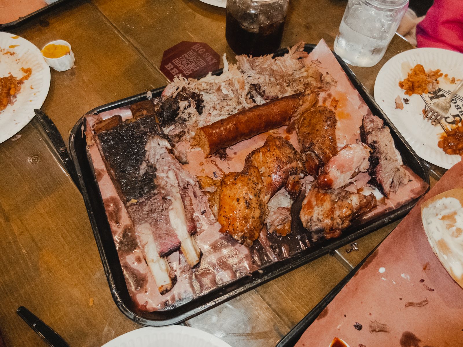 A tray of mixed barbecue with sliced brisket, sausage and pulled pork