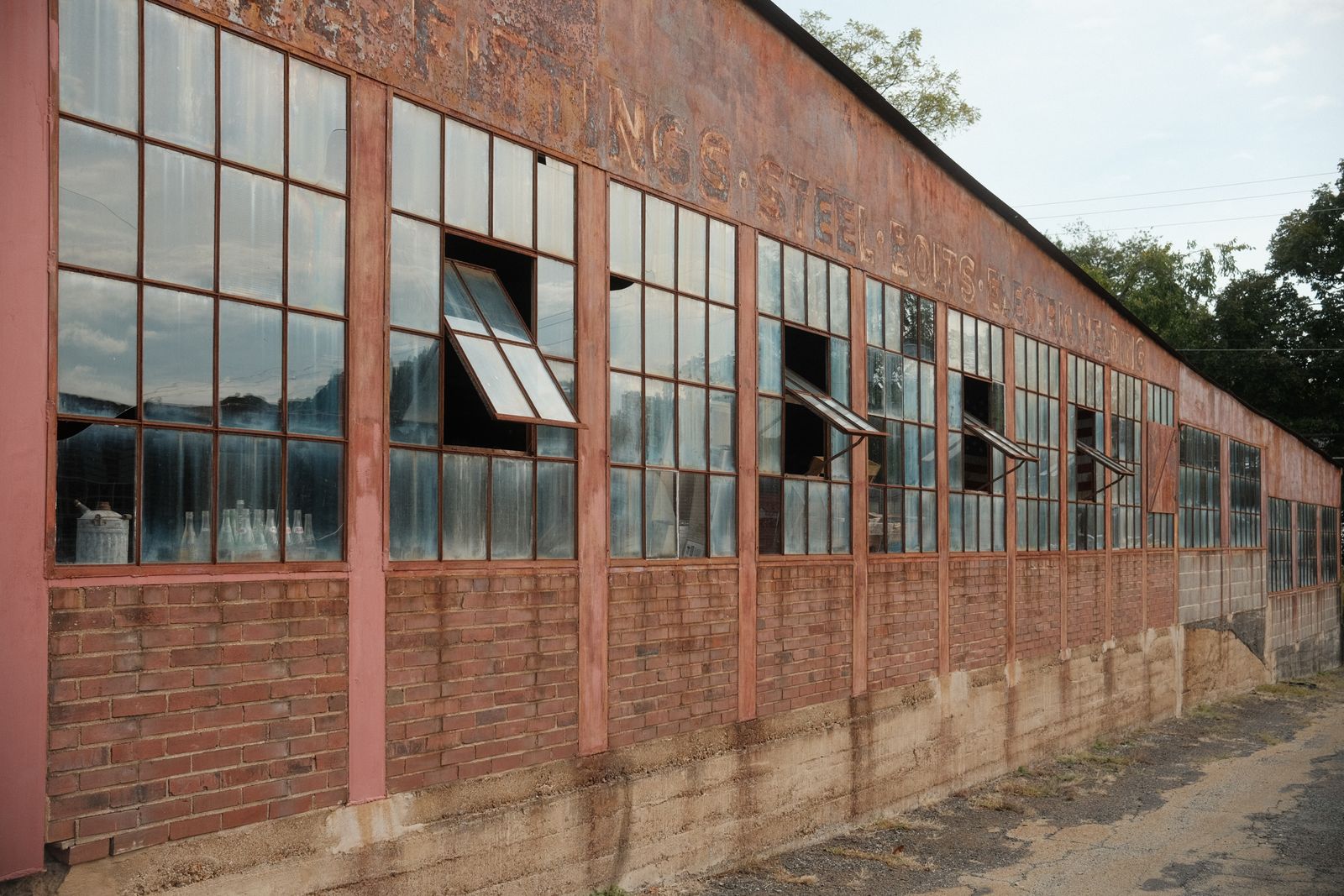 The long brick facade of an old industrial building with rows of tall windows