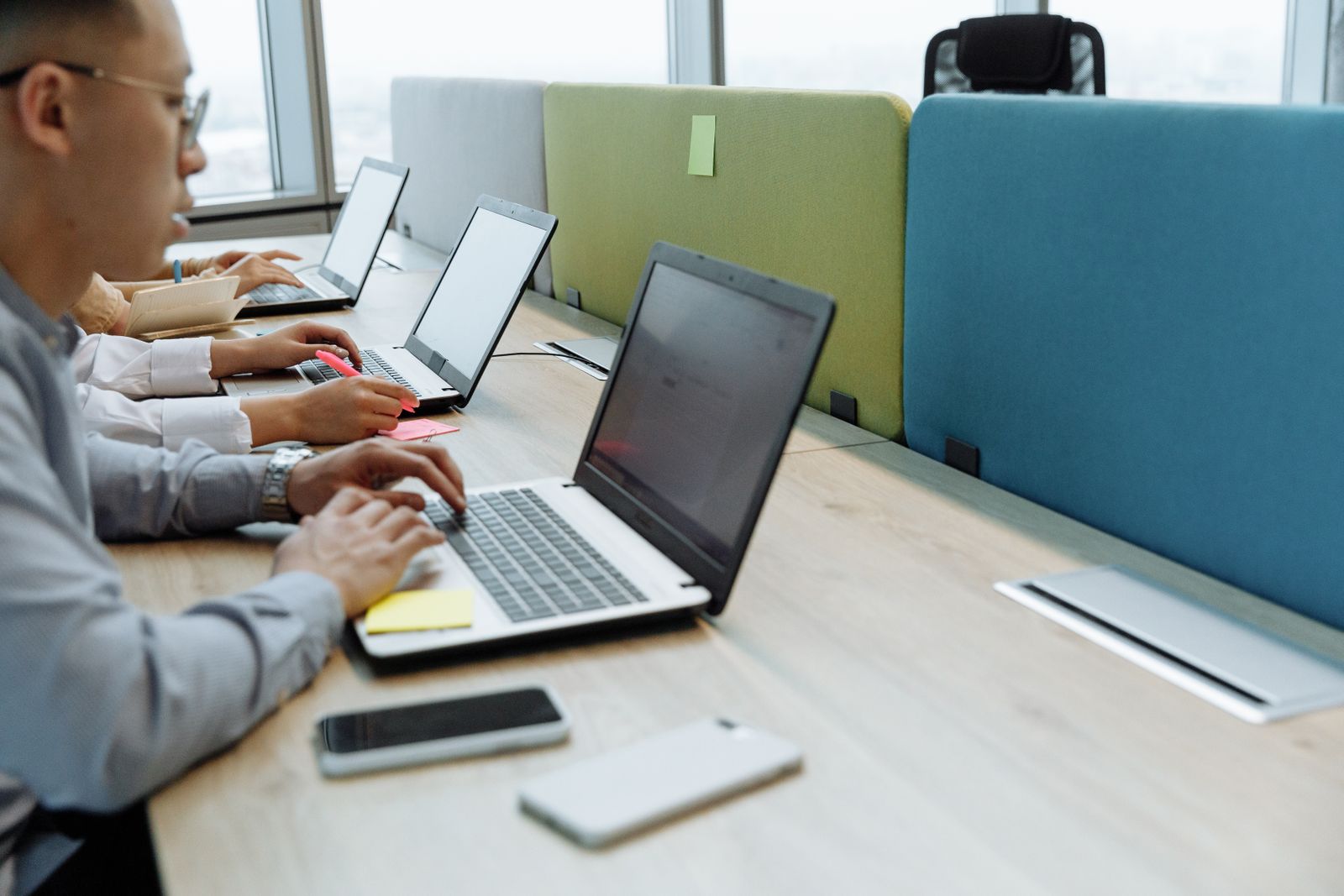 Hands typing on laptops at a shared desk
