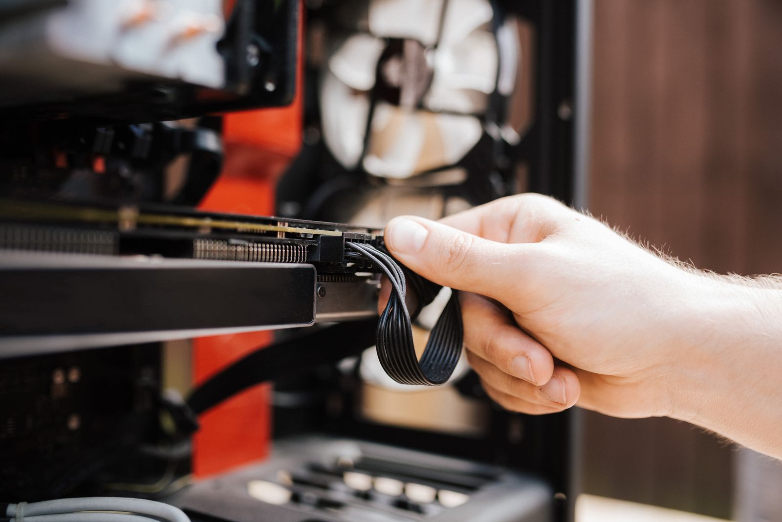 An engineer's hands connecting cables inside a desktop computer