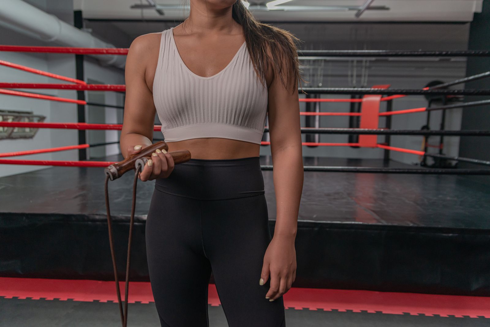 A woman holds a skipping rope in front of a boxing ring