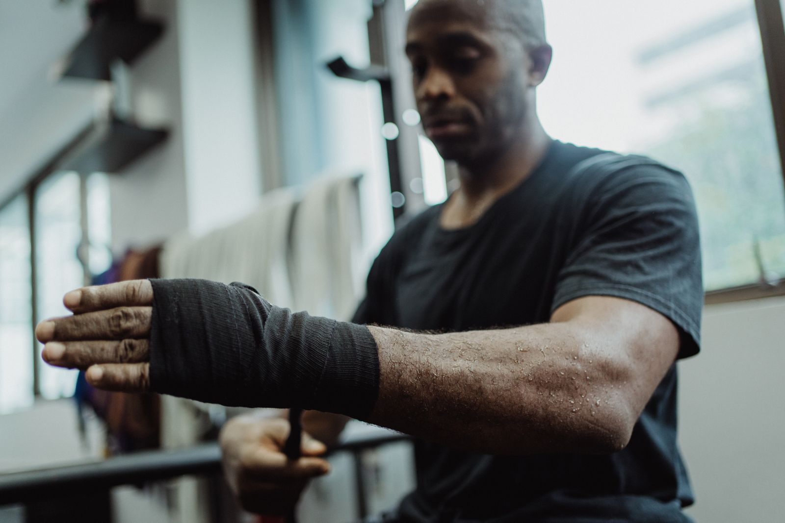 A man wraps his hand in black hand wraps before training