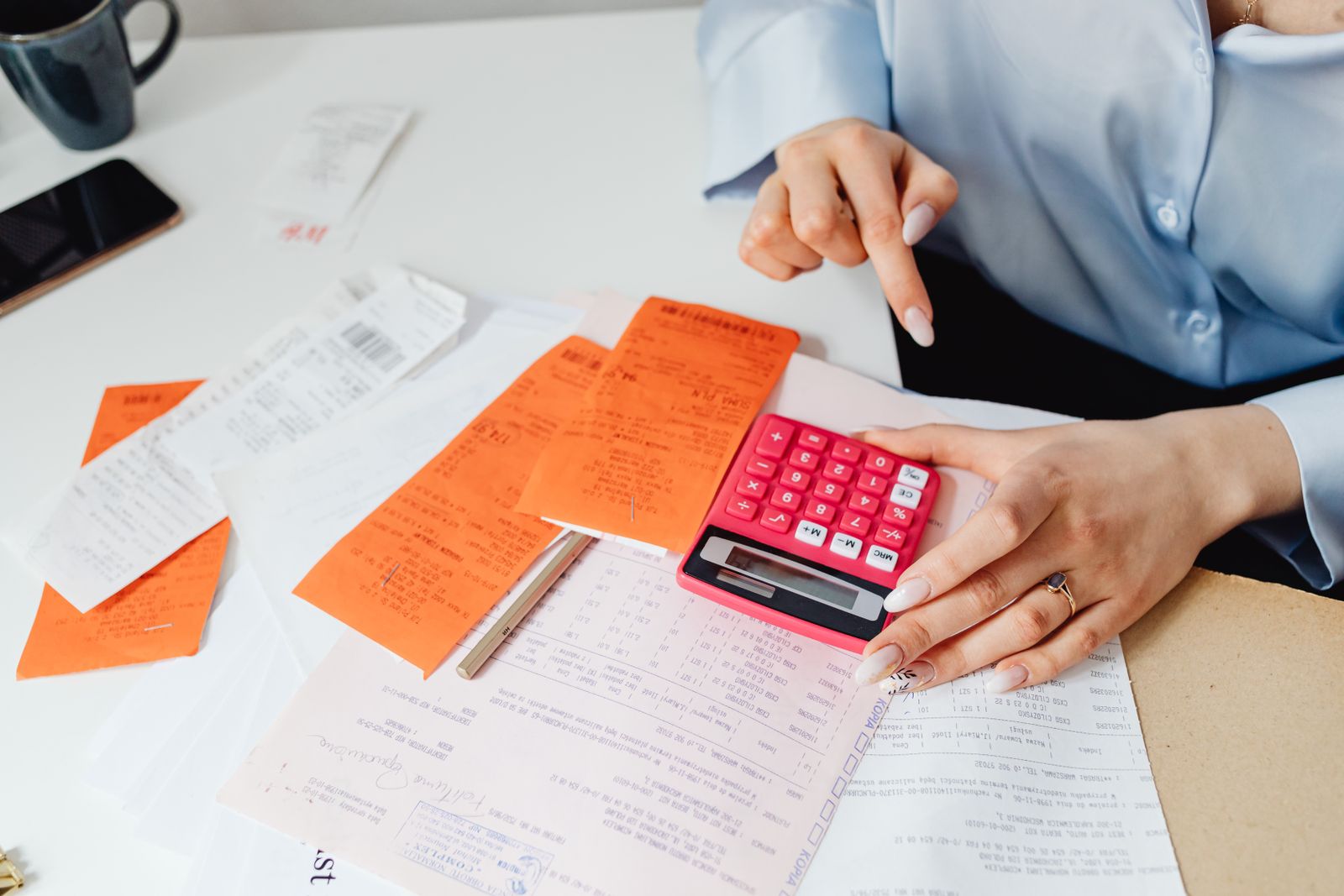 Hands working through receipts with a calculator on a desk