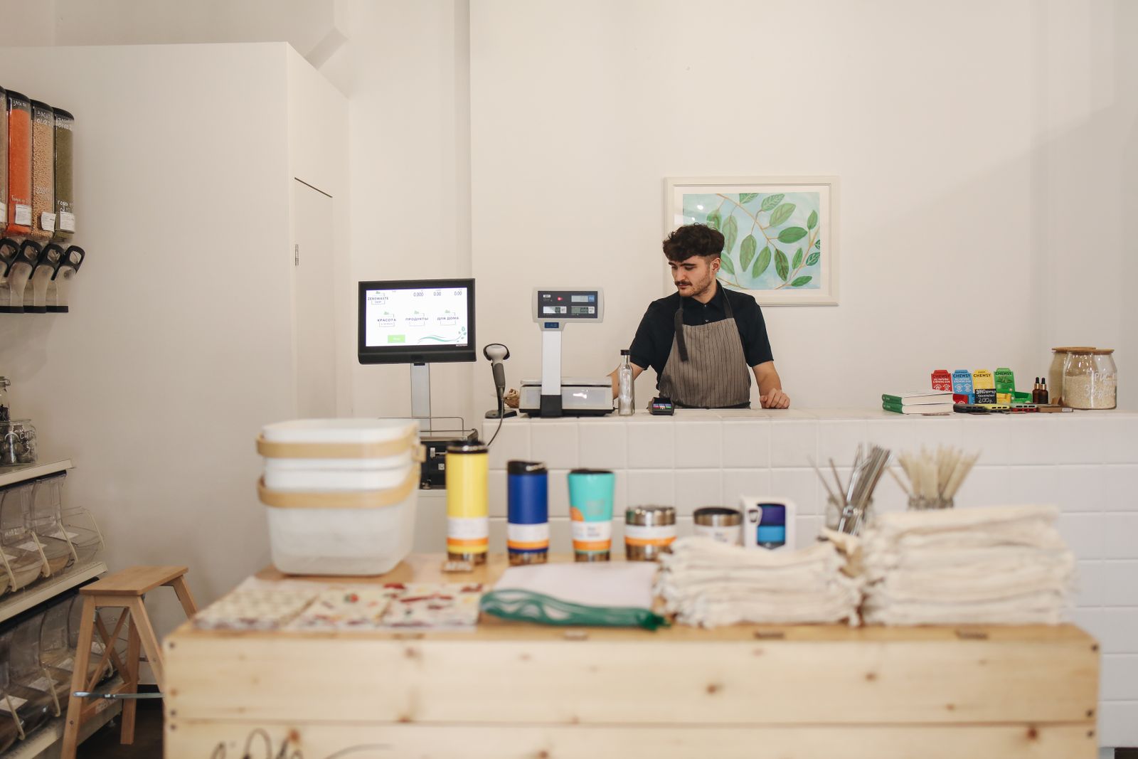 A shop owner behind the counter of a small refill store