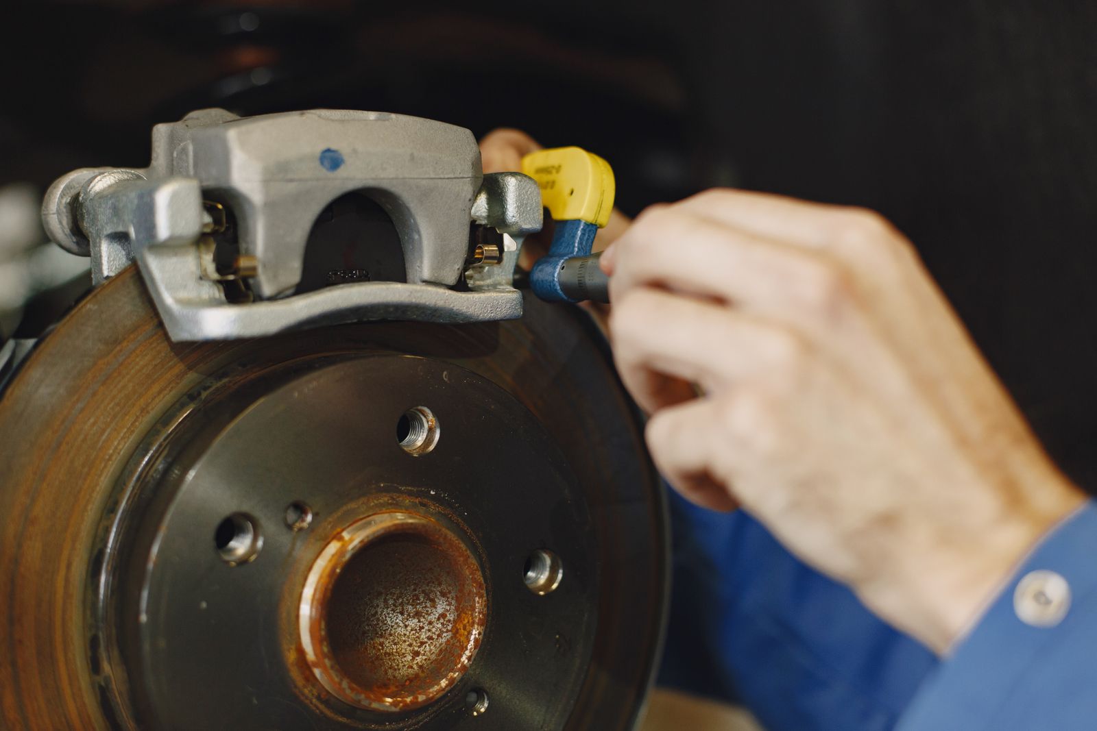 A technician's hands fitting a brake caliper over a disc