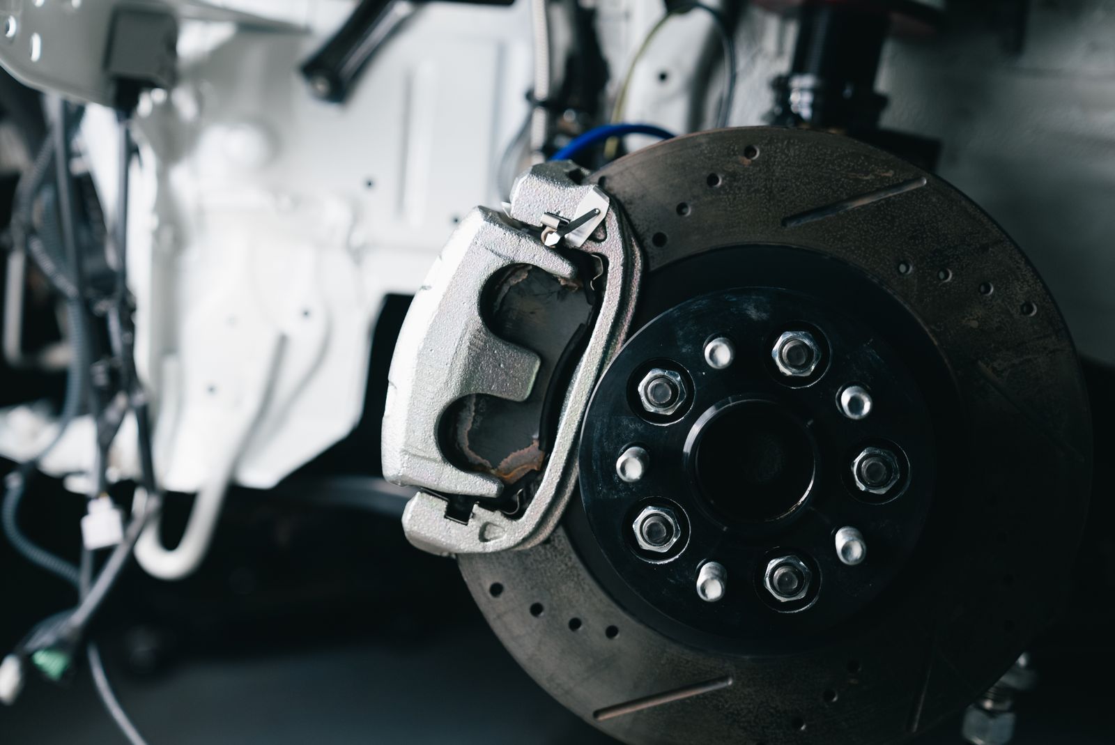 A drilled brake disc and caliper on a car in the workshop