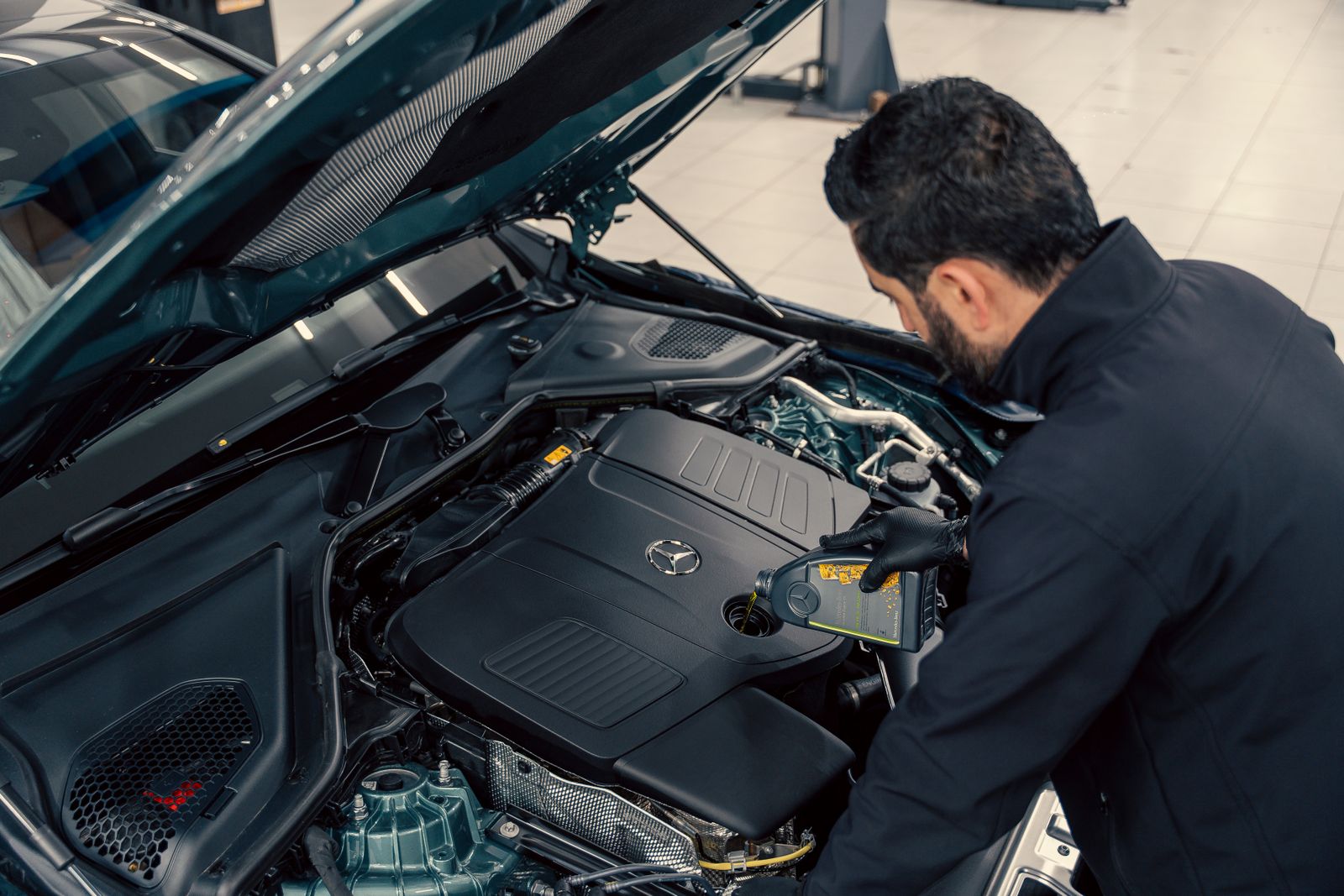 A technician leaning over the open engine bay of a car during a service