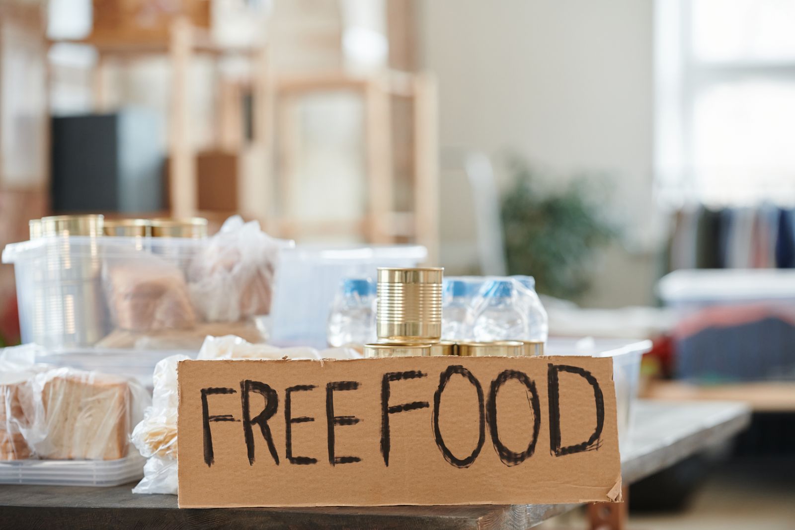 A table of bread and tins under a handwritten free food sign