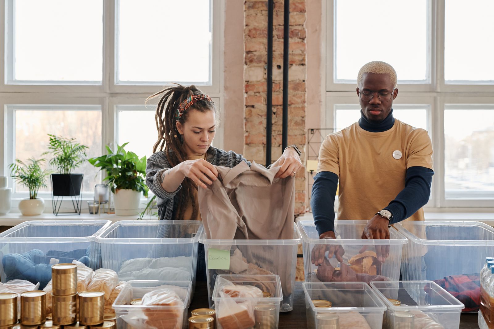 Two volunteers folding and sorting donations at a long table
