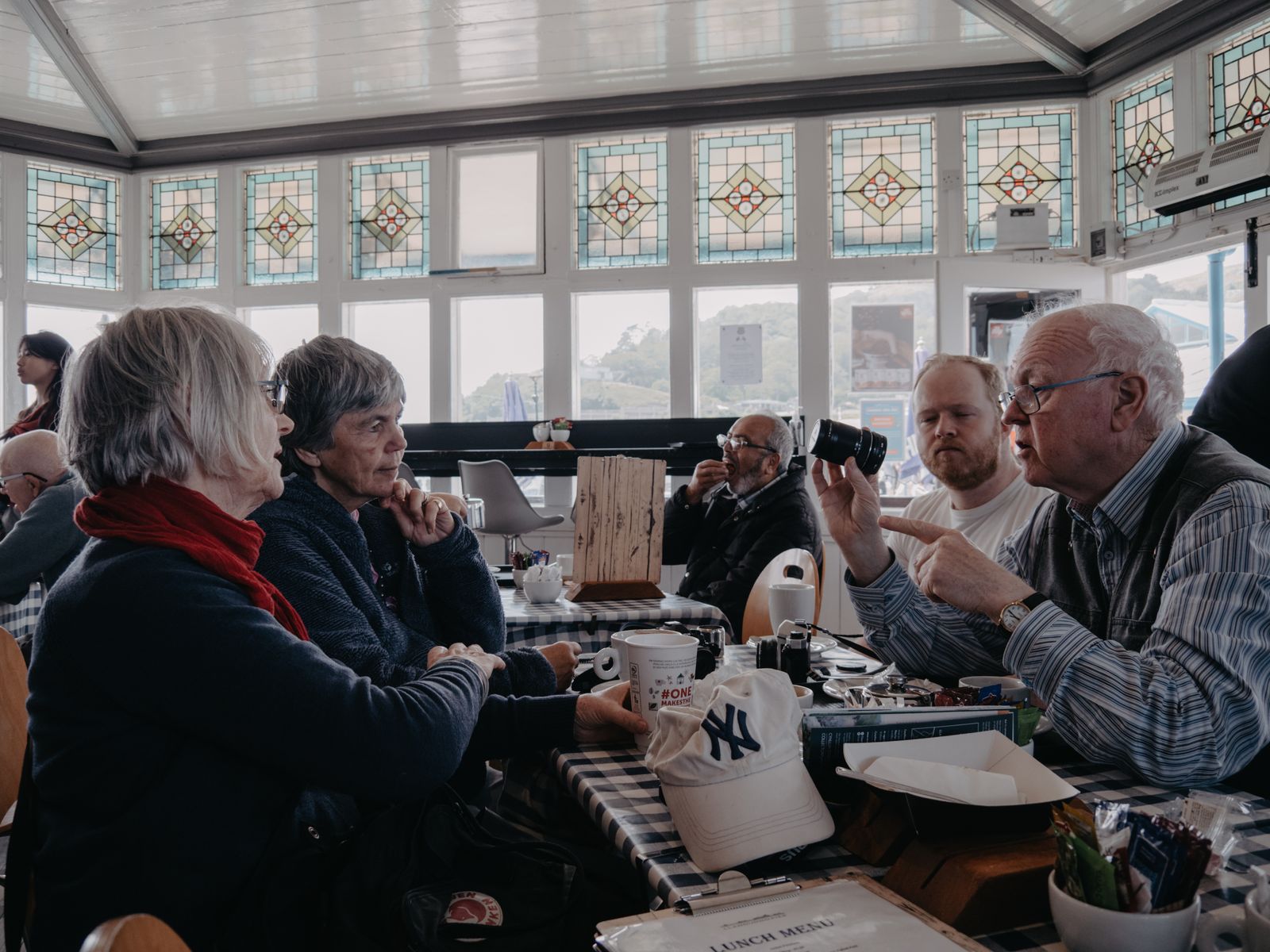 Older neighbours talking over coffee in a warm, light room