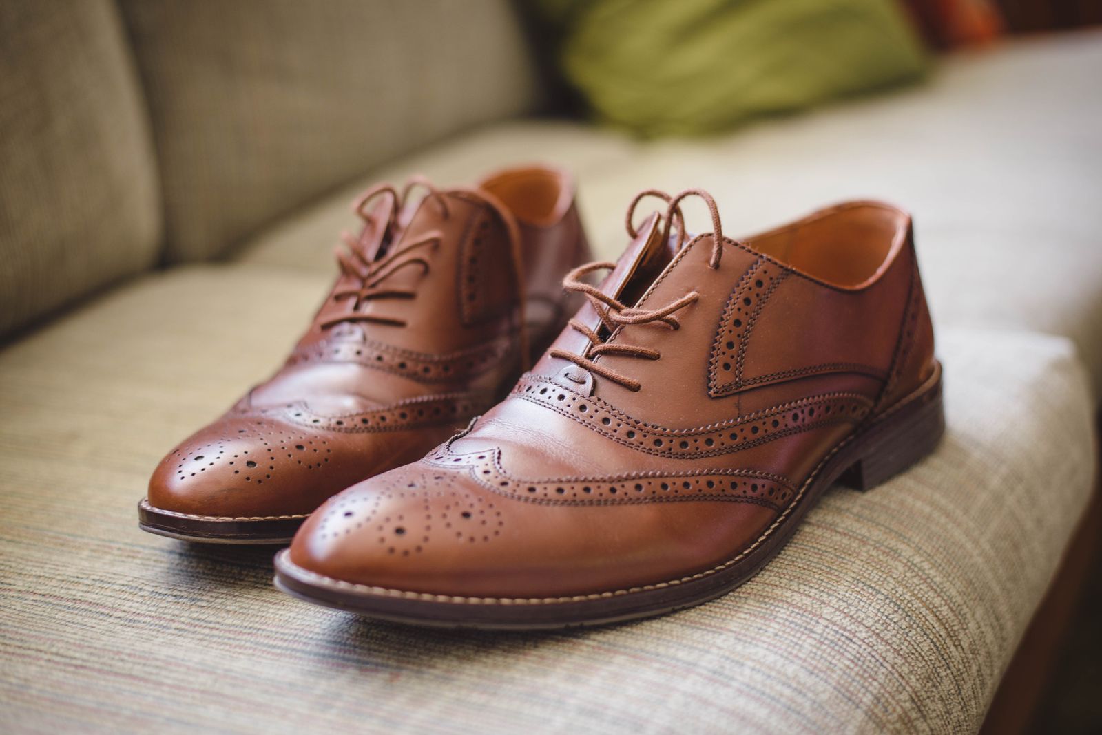 A pair of brown leather brogues with laces on a grey floor