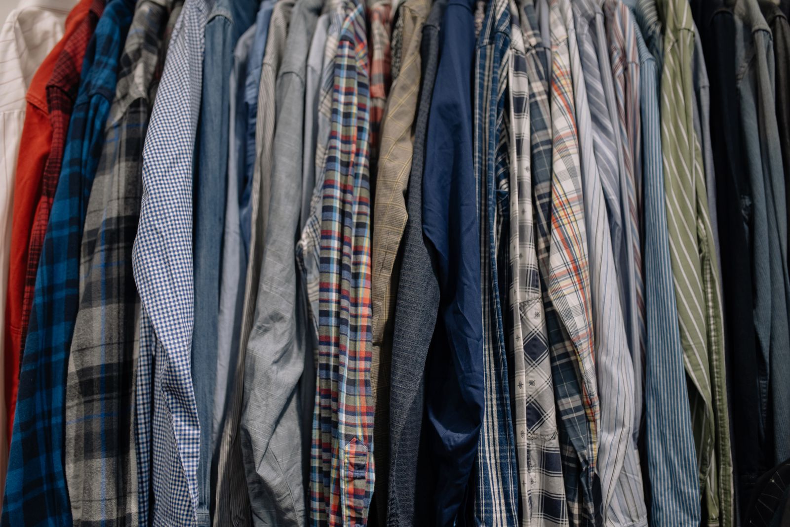 A rail of men's shirts in checks, stripes and plain blues, hanging close together