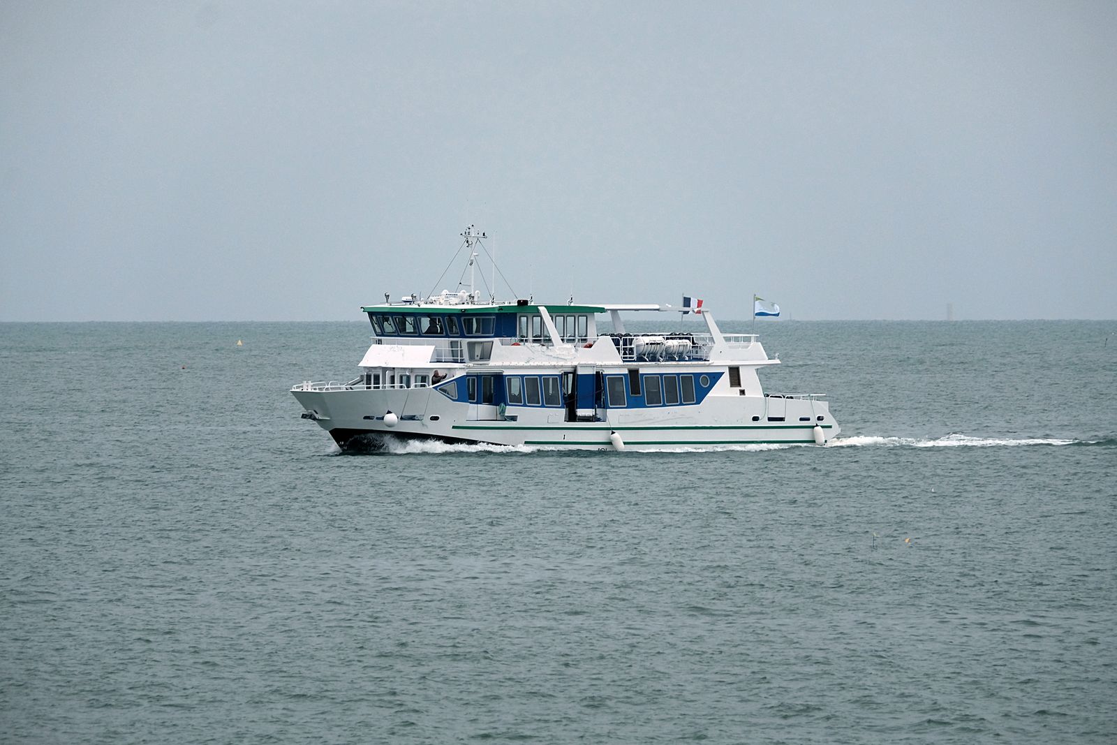 A white passenger boat crossing open water under a cloudy sky