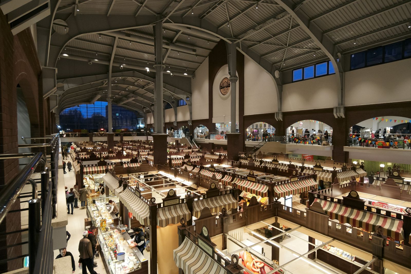 A large indoor market hall with food stalls under an arched roof