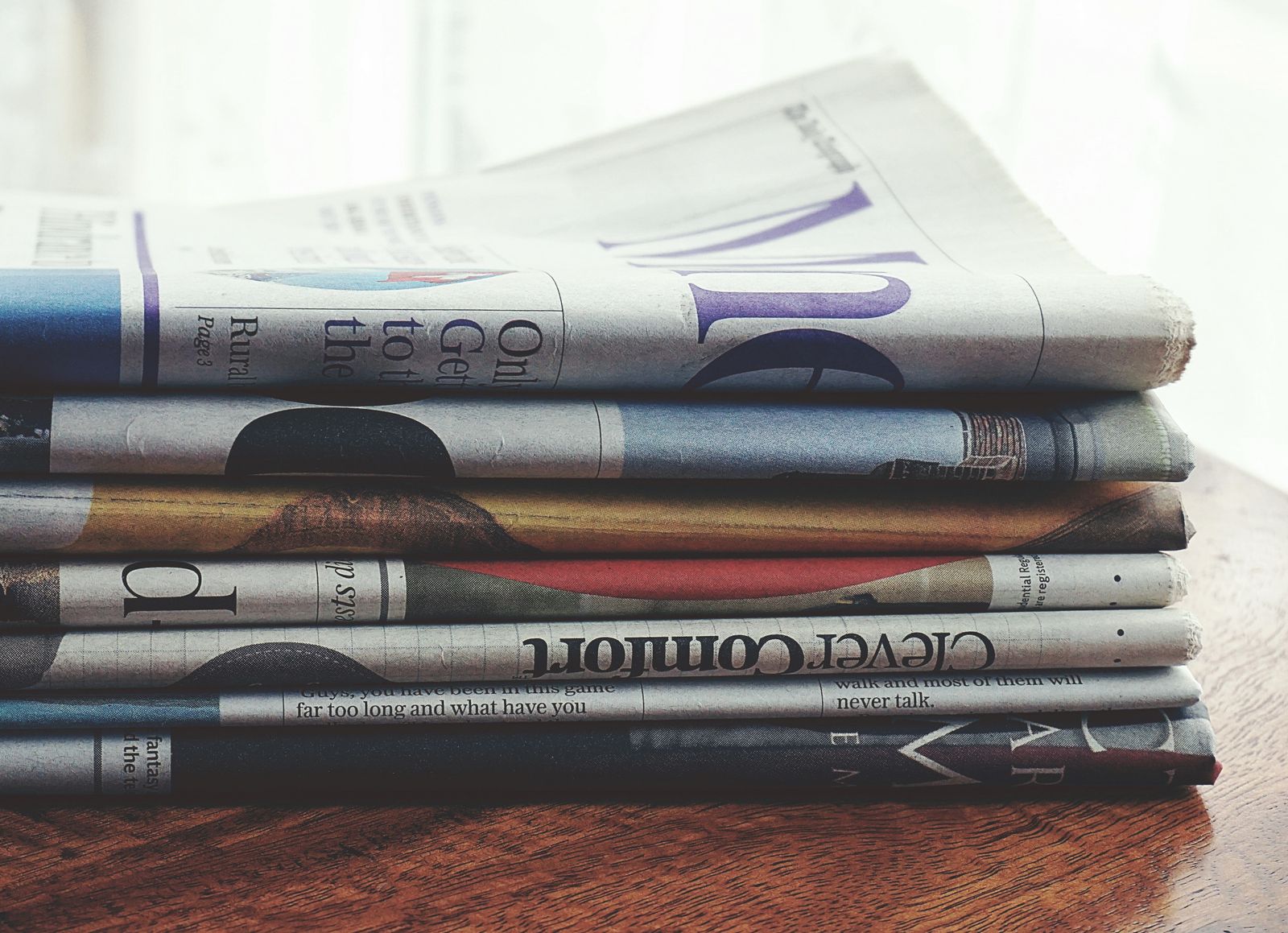 A pile of folded newspapers on a wooden table