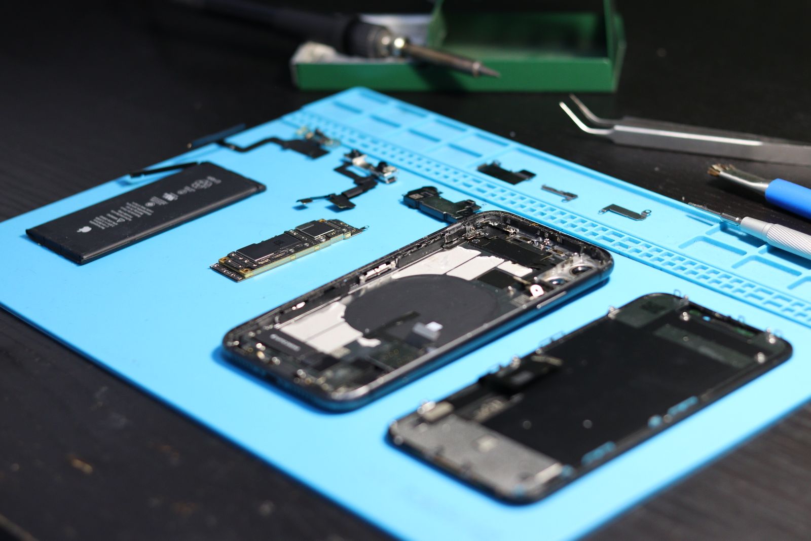 Phone parts and an opened phone laid out on a blue silicone repair mat