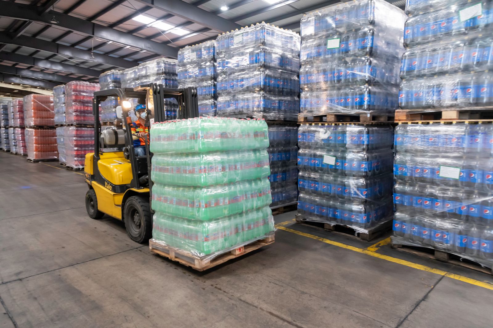 A forklift moving stacked pallets in a warehouse