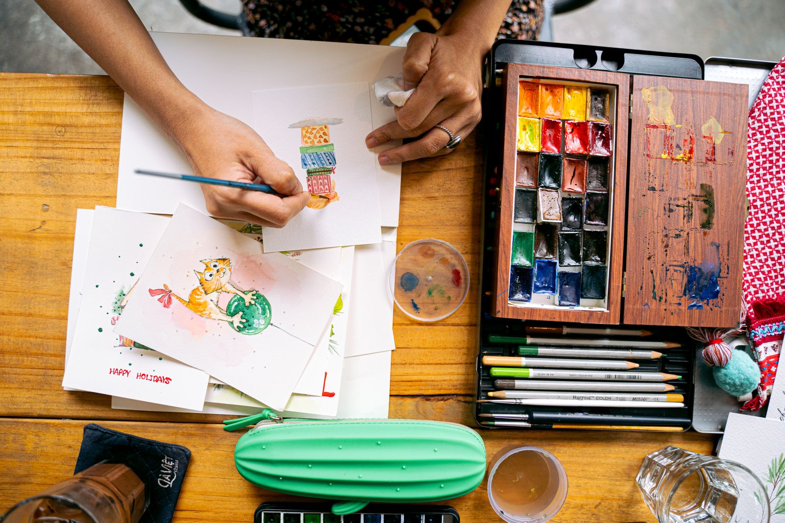 A watercolour painting in progress seen from above, with a palette and brushes