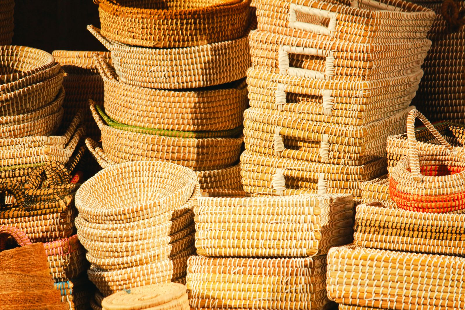 Stacks of handwoven seagrass baskets and trays in warm sunlight