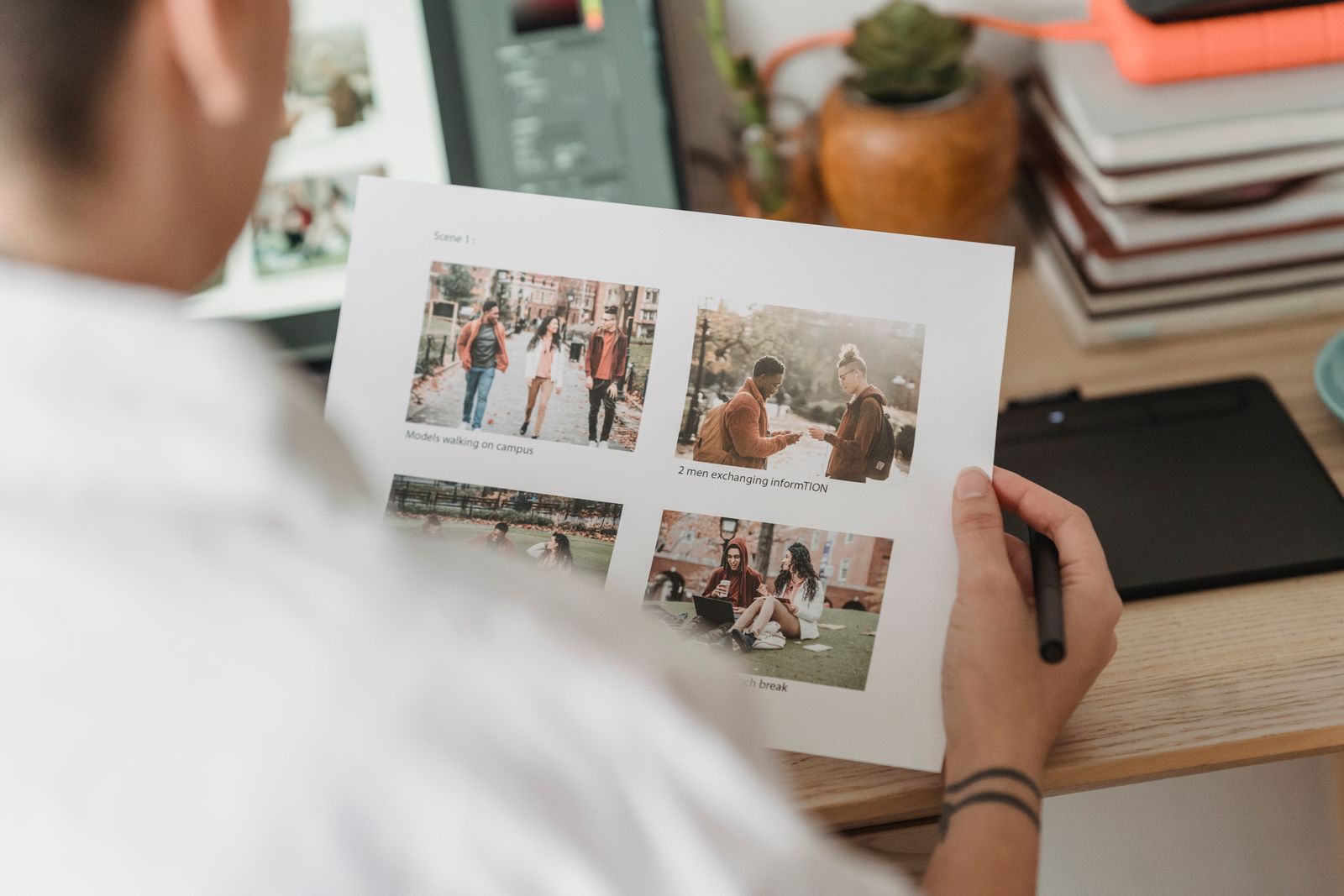 A designer checking a printed photo layout at a desk