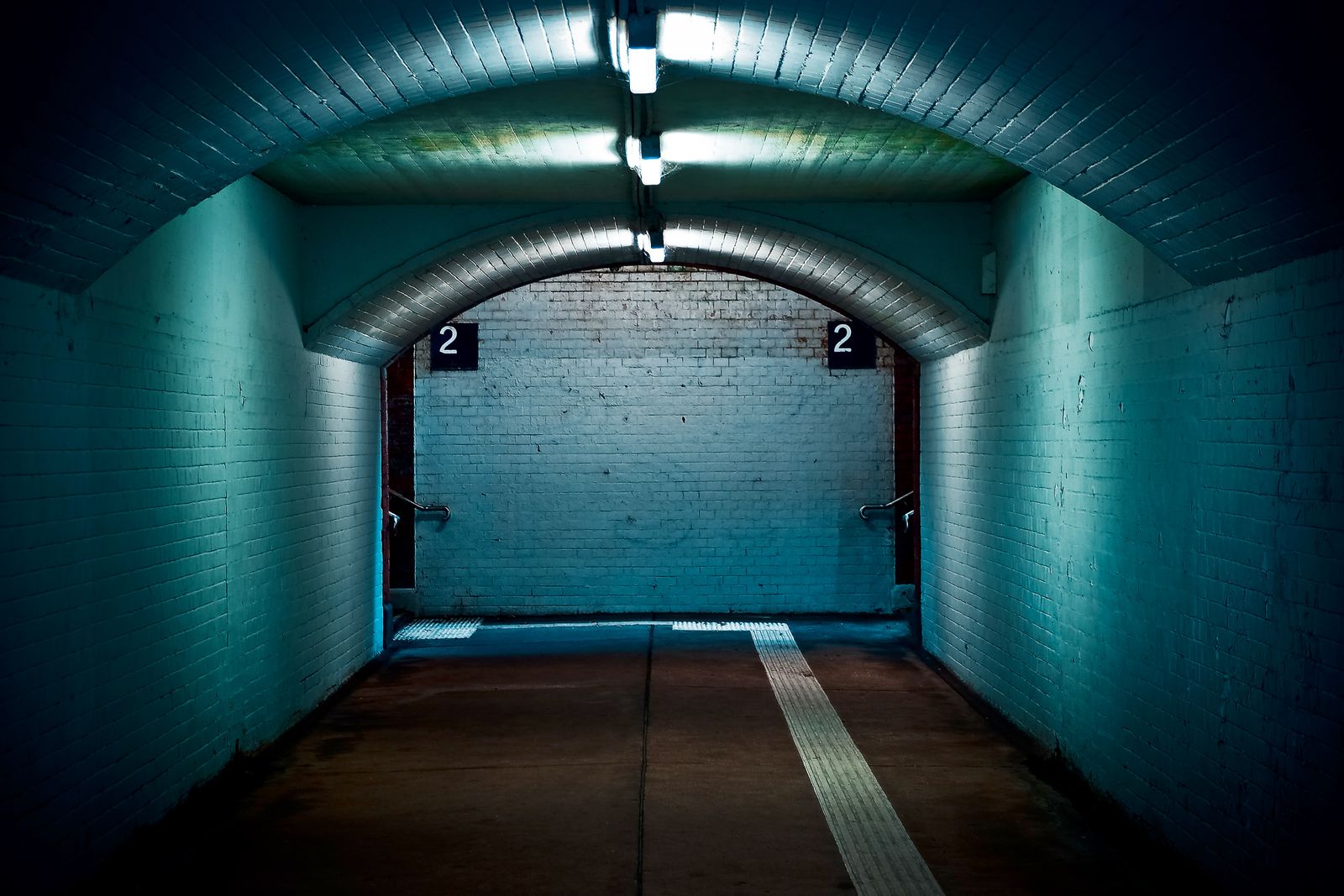 A tiled underpass with strip lights leading to the club entrance