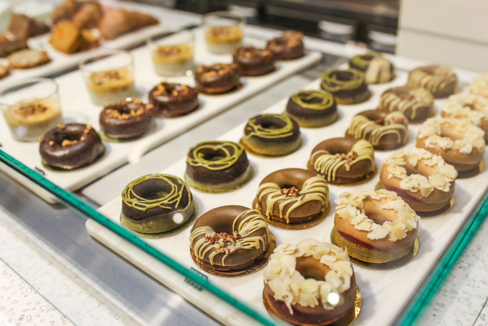 A tray of glazed and chocolate donuts in a bakery display case